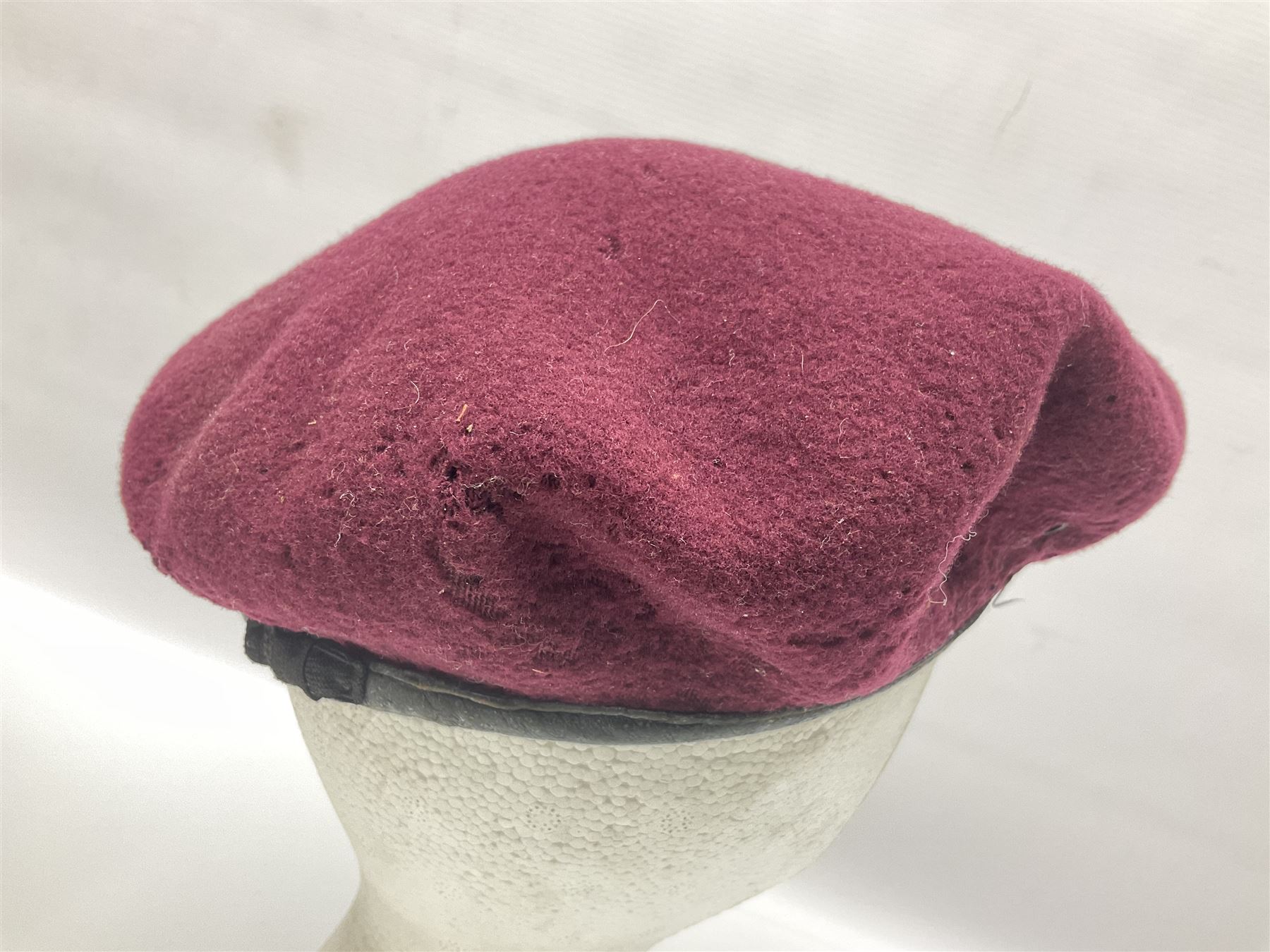 WW2 British Airborne Troops/Paratroopers Steel Helmet with green textured paint finish and netting cover, leather and sponge liner and three point chinstrap mounting; liner marked BMB 1943; together with a paratrooper's maroon beret with metal badge (2)