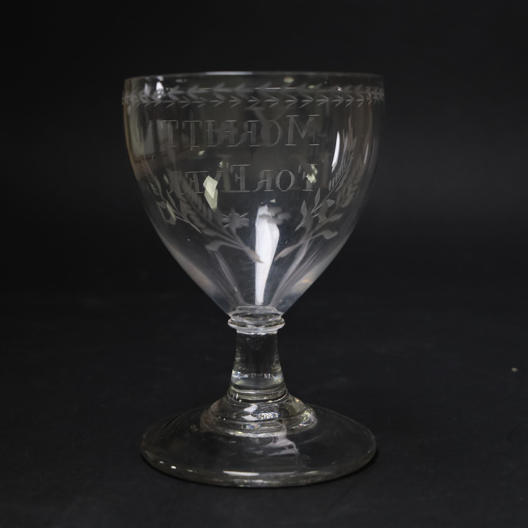 Early 19th century electioneering glass rummer, circa 1800-1830, the funnel bowl engraved with the inscription 'MORRITT FOREVER', and initials 'Y I M' verso, within leafy sprigs and beneath a husk band to rim, upon a plain short spreading stem, upon conical foot, H13.5cm

John Bacon Sawrey Morritt (circa 1772–1843) of Rokeby Park was a traveller, classical scholar, landowner, politician, and friend of Sir Walter Scott. He sat in Parliament for Beverley (1799–1802) and later for Northallerton (1814–1818), periods when fiercely contested elections often produced engraved drinking glasses as campaign propaganda, which were distributed in taverns and at election dinners. Examples connected to local candidates such as this are particularly scarce and survive as rare intersections of political history and material culture. 