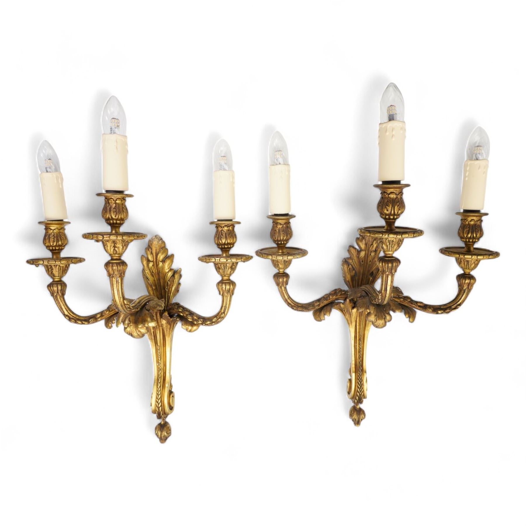 Pair of Lous XVI style ormolu three branch wall sconces, with scrolling foliate backplates and leaf-capped reeded scrolling branches, converted to electricity 