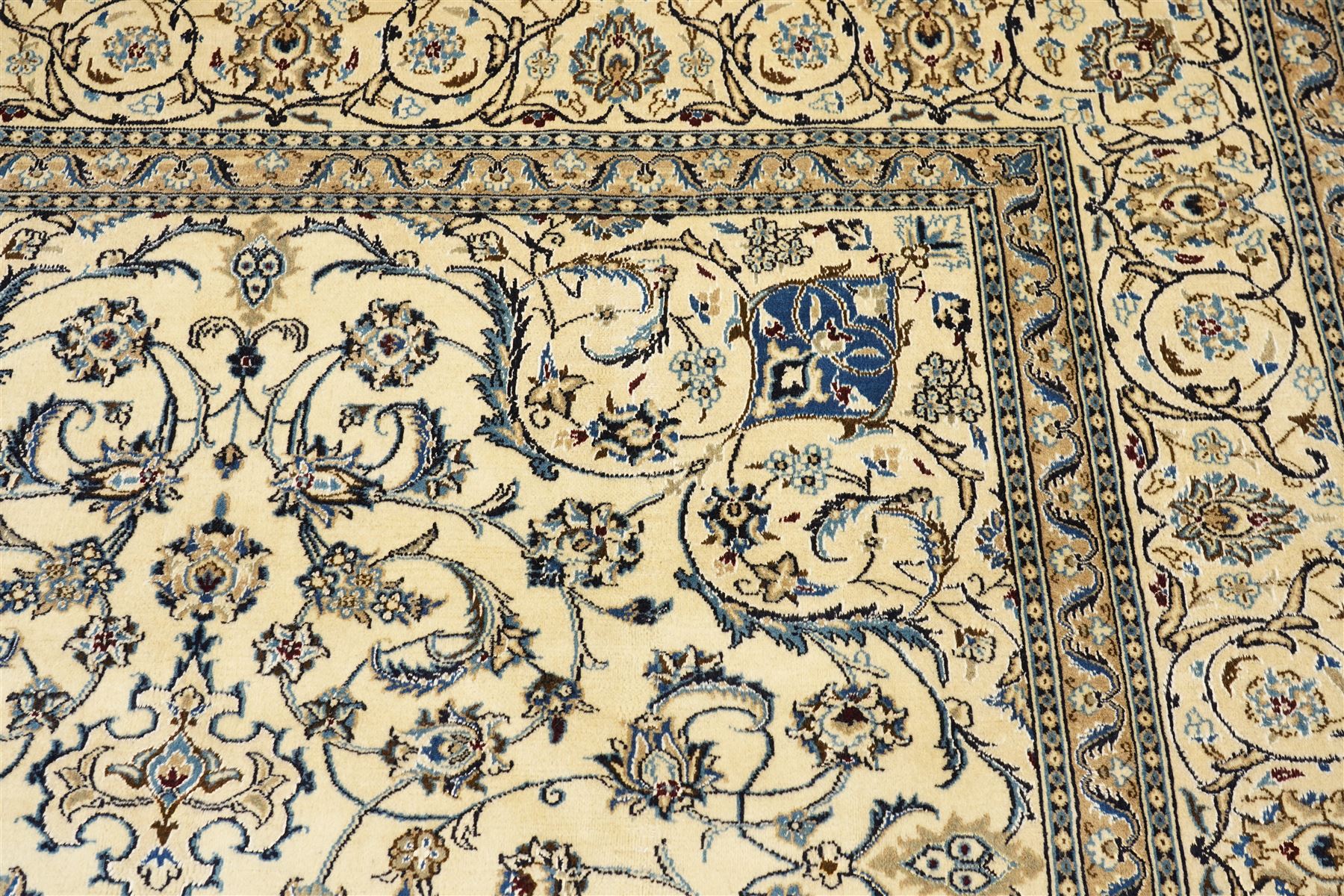 Central Persian Nain hand-knotted carpet, ivory field with central radiating medallion, issuing an all-over design of scrolling vines, palmettes, and delicate floral sprays with conforming spandrels, enclosed by a foliate border, framed by multiple guard stripes, with cotton fringe ends 