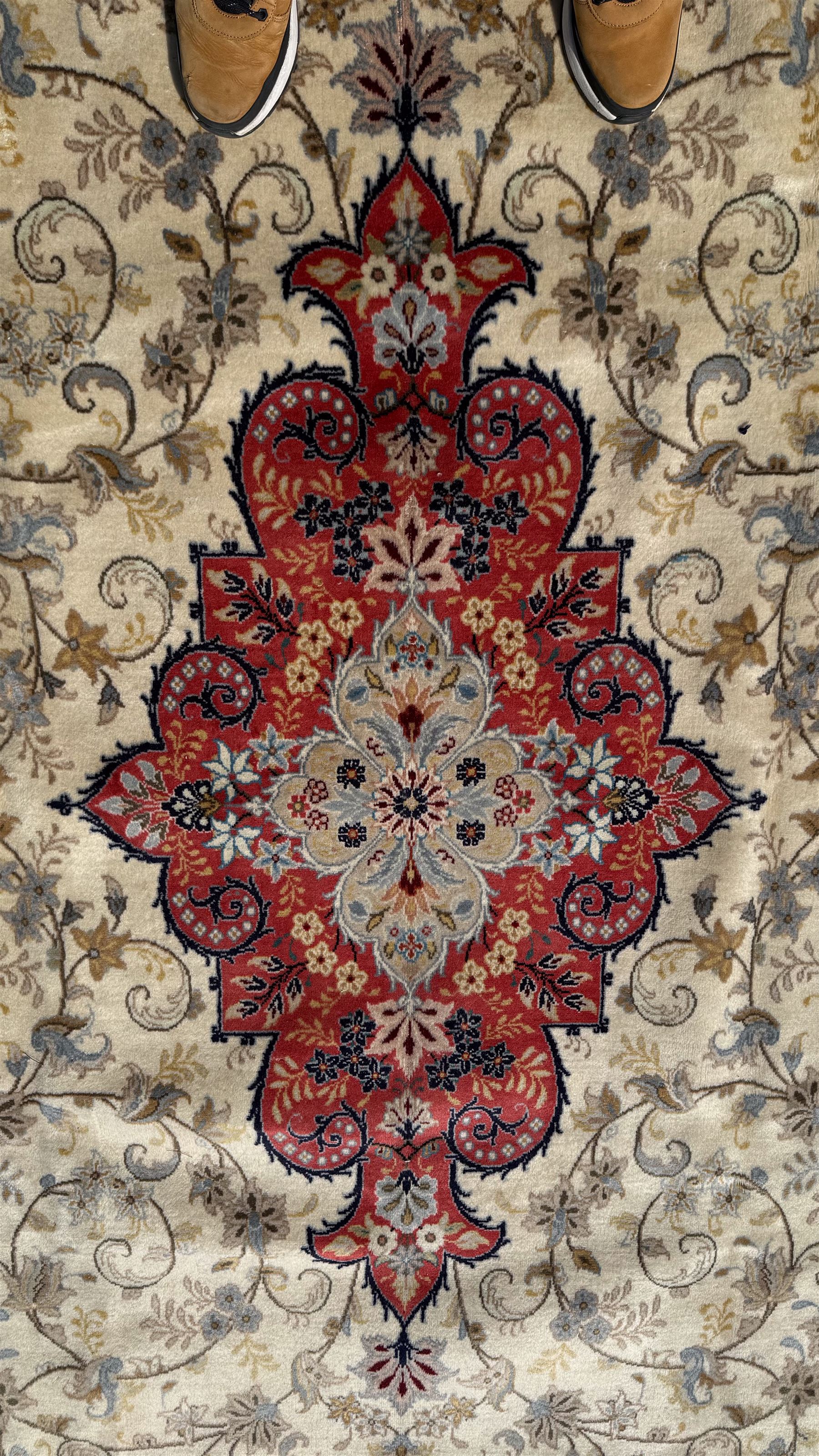 Central Persian Kashan rug, ivory and teal ground, overall geometric design, angular interlaced decorated field with stylised plant motifs, crimson ground, central medallion, the crimson main border band decorated with geometric motifs