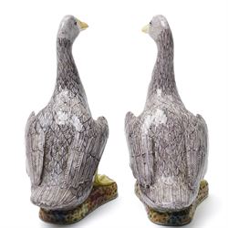 Pair of 20th century Chinese Export porcelain ducks, each naturalistically modelled with aubergine and white enamel plumage and seated on polychrome rockwork bases, H24cm 