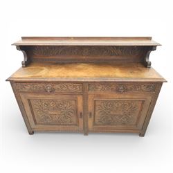Victorian carved oak sideboard, the rectangular top with raised back carved with foliate scrolls and scroll end supports, upon a base with rectangular top with moulded edge, pair of drawers with conforming carved decoration and mask handles, and pair of carved cupboard doors, upon short stile type feet H101.5cm W183cm D54cm 