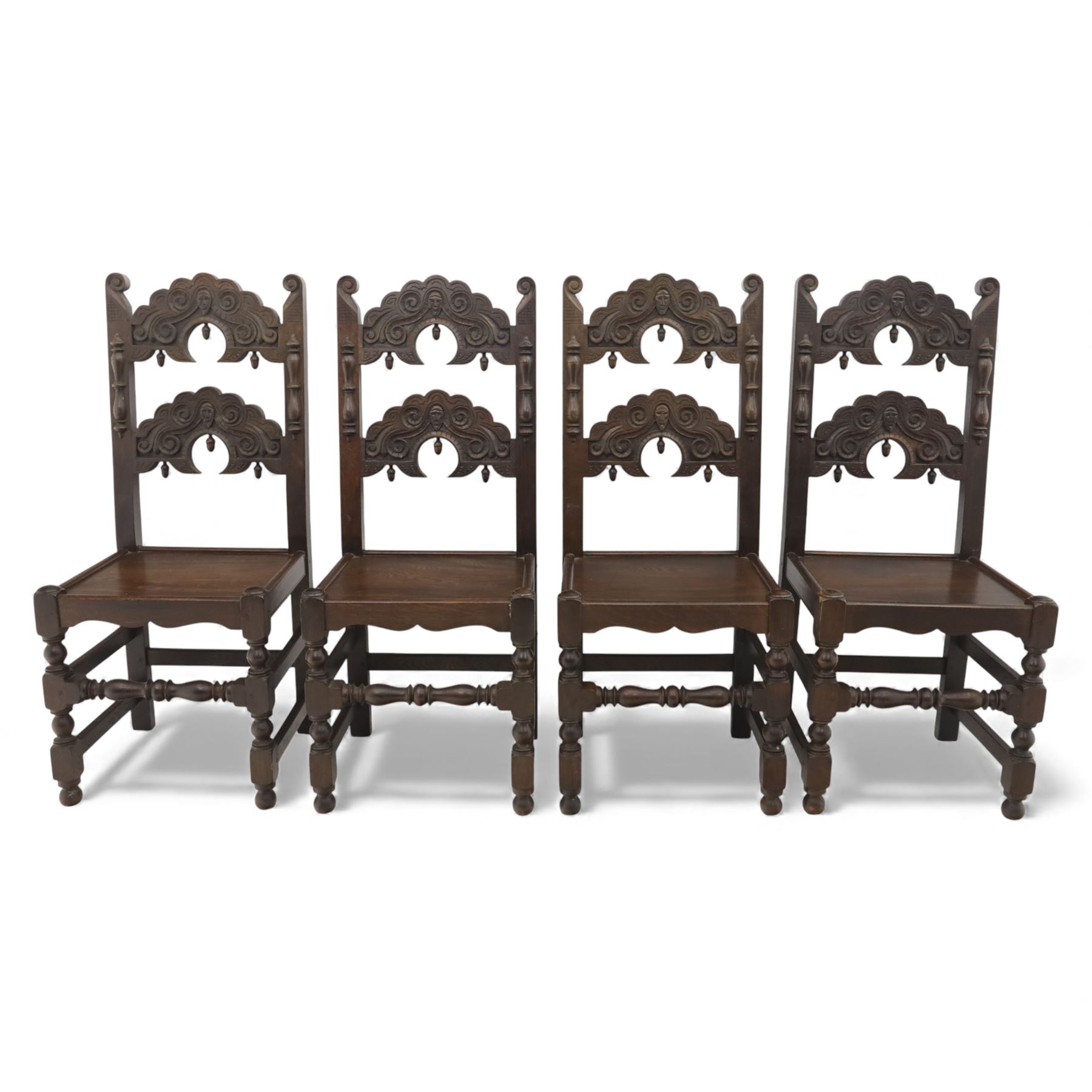 Early 20th century set of seven Jacobean Revival oak chairs, comprising pair of cavers and five chairs, each with carved mask and scroll decoration to the crest and and back rail, plain oak seat, upon turned front legs and block rear legs with conforming stretchers