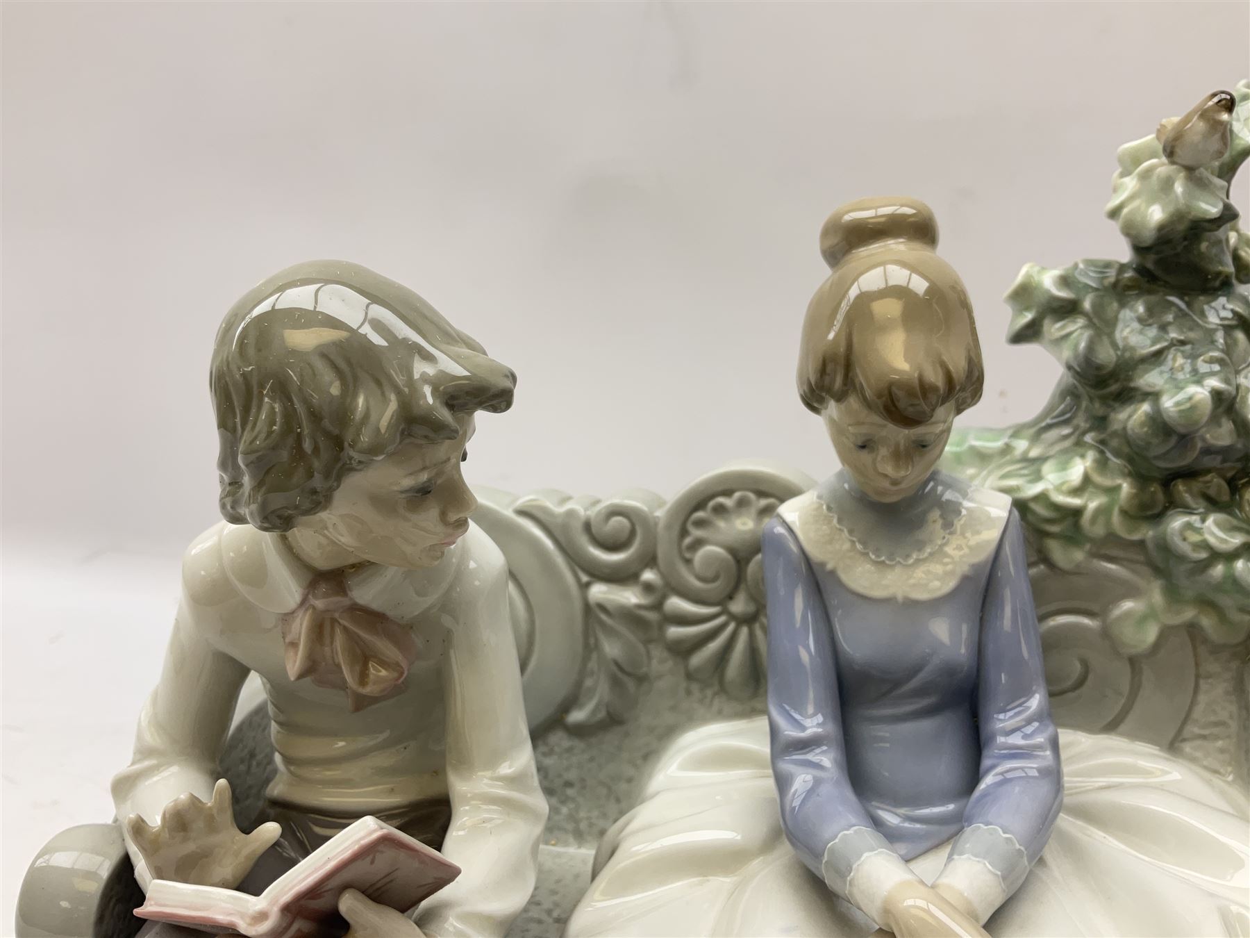 Lladro figure, Poetry of Love, modelled as a boy seated reading from a book next to a girl on garden bench with a dog at her feet, sculpted by Regino Torrijos, with original box, no 5442, year issued 1987, year retired 1998, H22cm