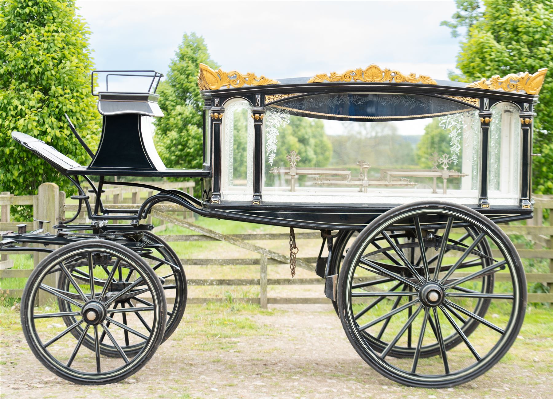 Victorian Glass Hearse

A black painted four wheeled horse drawn glass hearse with extensively glazed coffin compartment, etched glass side and end panels, decorative gilt cresting, gilt column capitals, white painted interior bier deck, metal coffin rails with cross finials, rear glazed access doors, external coachman's box seat for two, wooden spoked wheels the wheel hubs stamped 'The Economic Funeral Co', leaf spring suspension, underbody turntable steering and pole for driving with a pair of horses. The hearse has decorative painted lining throughout and an ornate black and gilt body with curved glass panels to the sides and rear.

Features

• Extensively glazed coffin compartment
• Etched glass side and end panels
• Decorative gilt cresting
• Gilt column capitals
• White painted interior bier deck
• Metal coffin rails with cross finials
• Rear glazed access doors
• External coachman's box seat
• Wooden spoked wheels
• Leaf spring suspension
• Underbody turntable steering
• Pole for driving with a pair of horses
• Decorative painted lining

Dimensions:
Overall length: 406 cm
Body length: 250 cm
Overall width: 190 cm
Body width: 115 cm
Height: 228 cm

Wheel Diameters:
Front wheels: 102 cm
Rear wheels: 133 cm

Seating

Coachman's box seat: 2