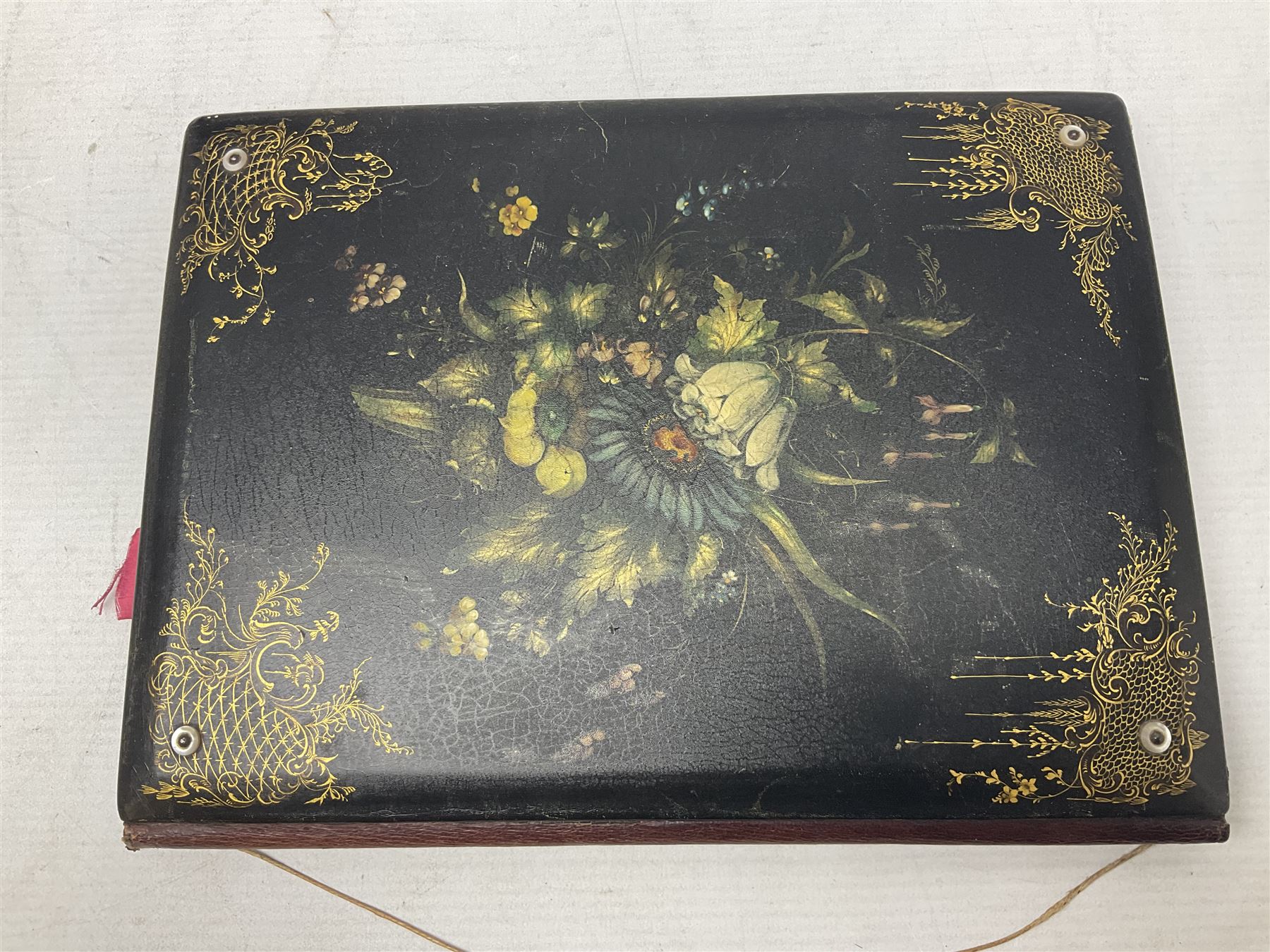Victorian desk ink blotter, decorated with painted spray of flowers within stylised gilt rococo spandrels with mother of pearl fixings, together with a Victorian photo album containing interior leaves with apertures of various sizes and shapes of portraits surrounded by printed sea and dock scenes, blotter L28cm