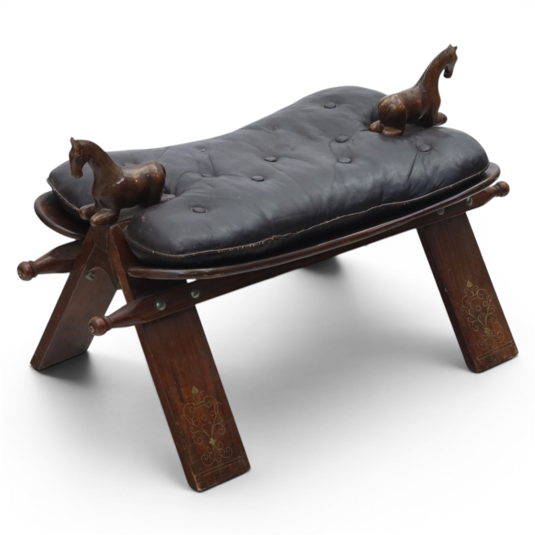 20th century saddle stool, wiht black leather seat, surmounted with carved horses, on an X-frame base with brass inlay