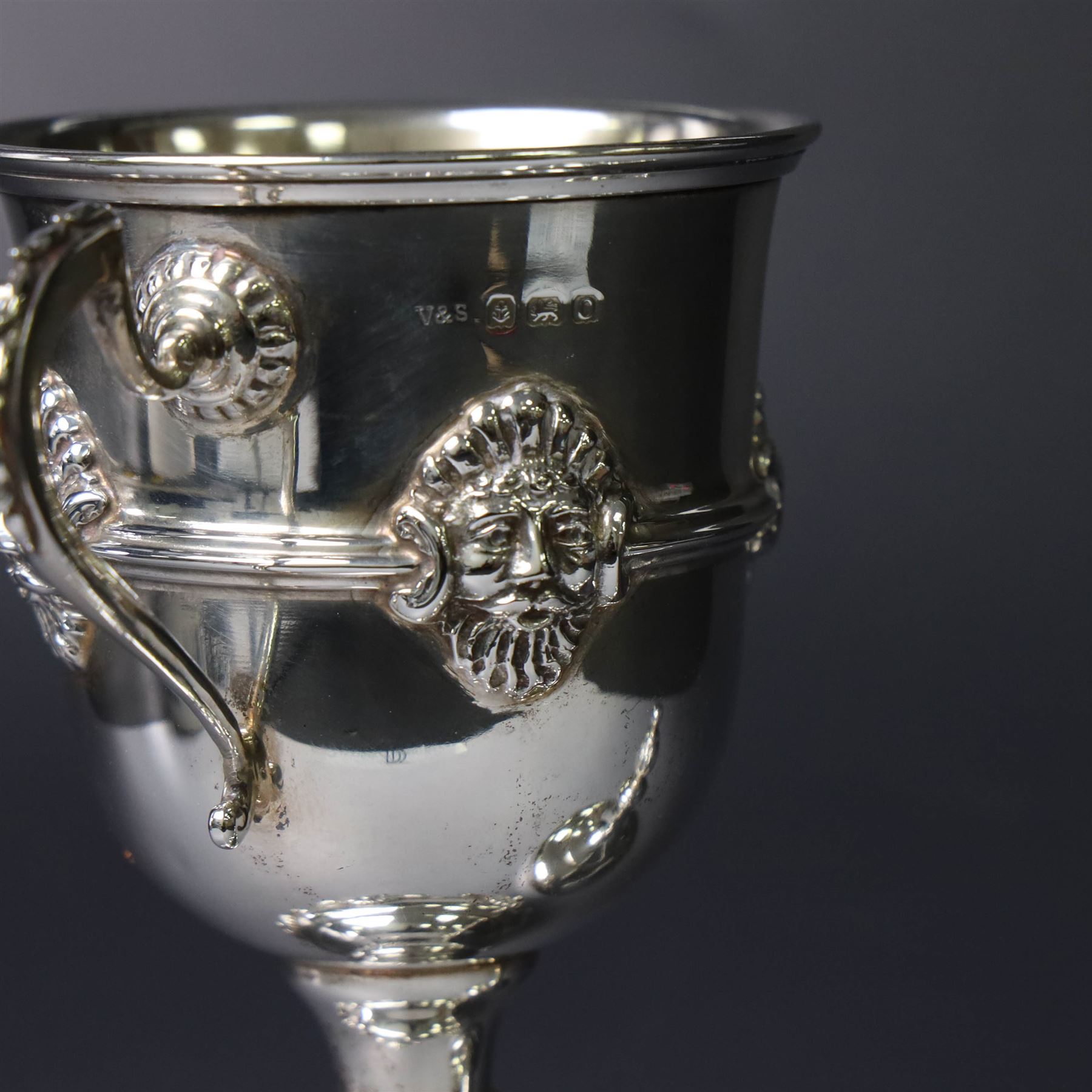 Mid 20th century silver twin handled trophy cup and cover, the bowl with central mask mounted girdle upon a knopped stem and spreading circular foot with flower head mounted paw feet, the tapering stepped cover with leaf moulded knop finial, hallmarked Vaughton & Sons, Birmingham 1938