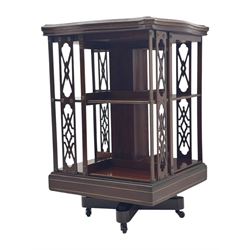 Edwardian inlaid mahogany revolving bookcase, shaped square moulded top with central motif and satinwood band, two tiers with pierced vertical splats, on swivel action base with ceramic castors