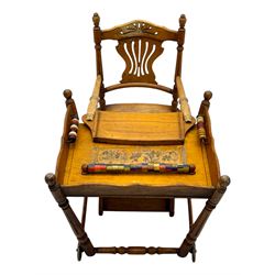 Late 19th century American oak child's metamorphic high chair and play table, carved spindle backrest with pierced splat, detachable tray with abacus and hand painted pastoral decoration, on turned supports with metal wheels