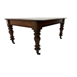 Mid-19th century mahogany dining table, rectangular top with moulded edge over banded frieze, raised on turned and lappet carved supports terminating in brass cups and castors