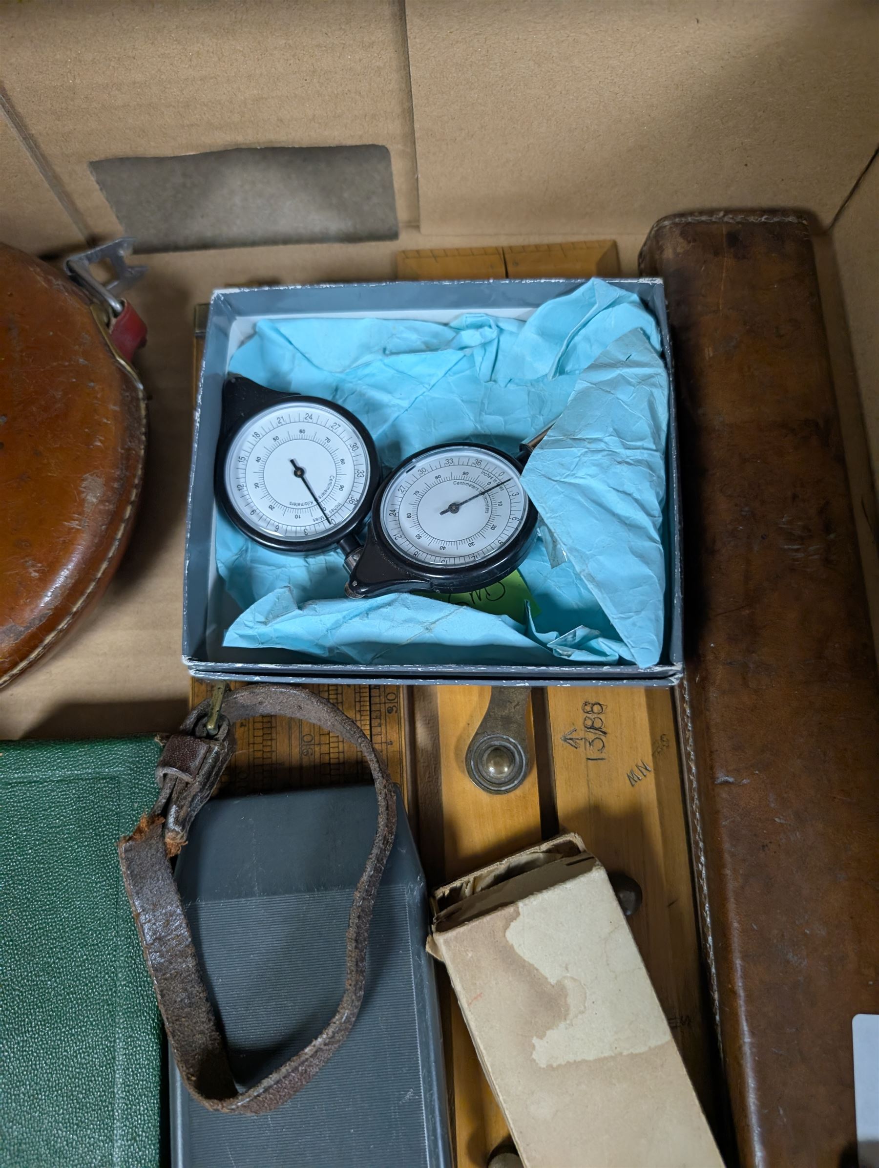 Three Rabone tape measures in leather cases, one with broad arrow, three map wheels, pair of Moore & Wright calipers, W Harling alidade in Whippy leather case with broad arrow and a collection of slide rules