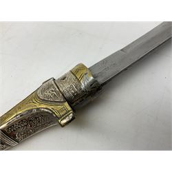 Moroccan Jambiya with 22.5cm curving steel blade, white metal and brass hilt with filigree and foliate engraved all over decoration with traces of coloured background; matching scabbard with two suspension loops L41cm overall