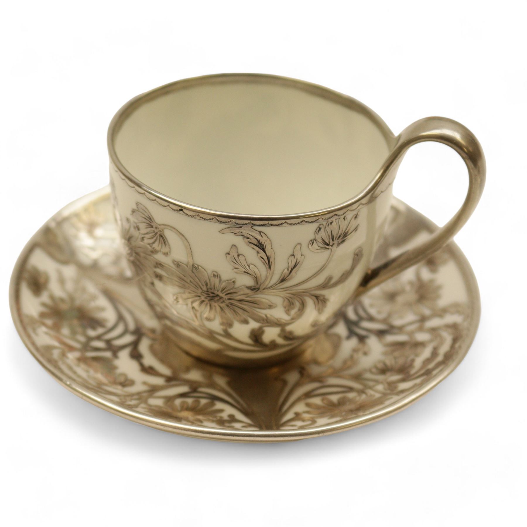 Three Pirkenhammer cups and saucers, two decorated with gilt birds in foliage on an ivory ground, the other with butterflies and foliate sprigs together with three  continental cups and saucers decorated with silver overlay 