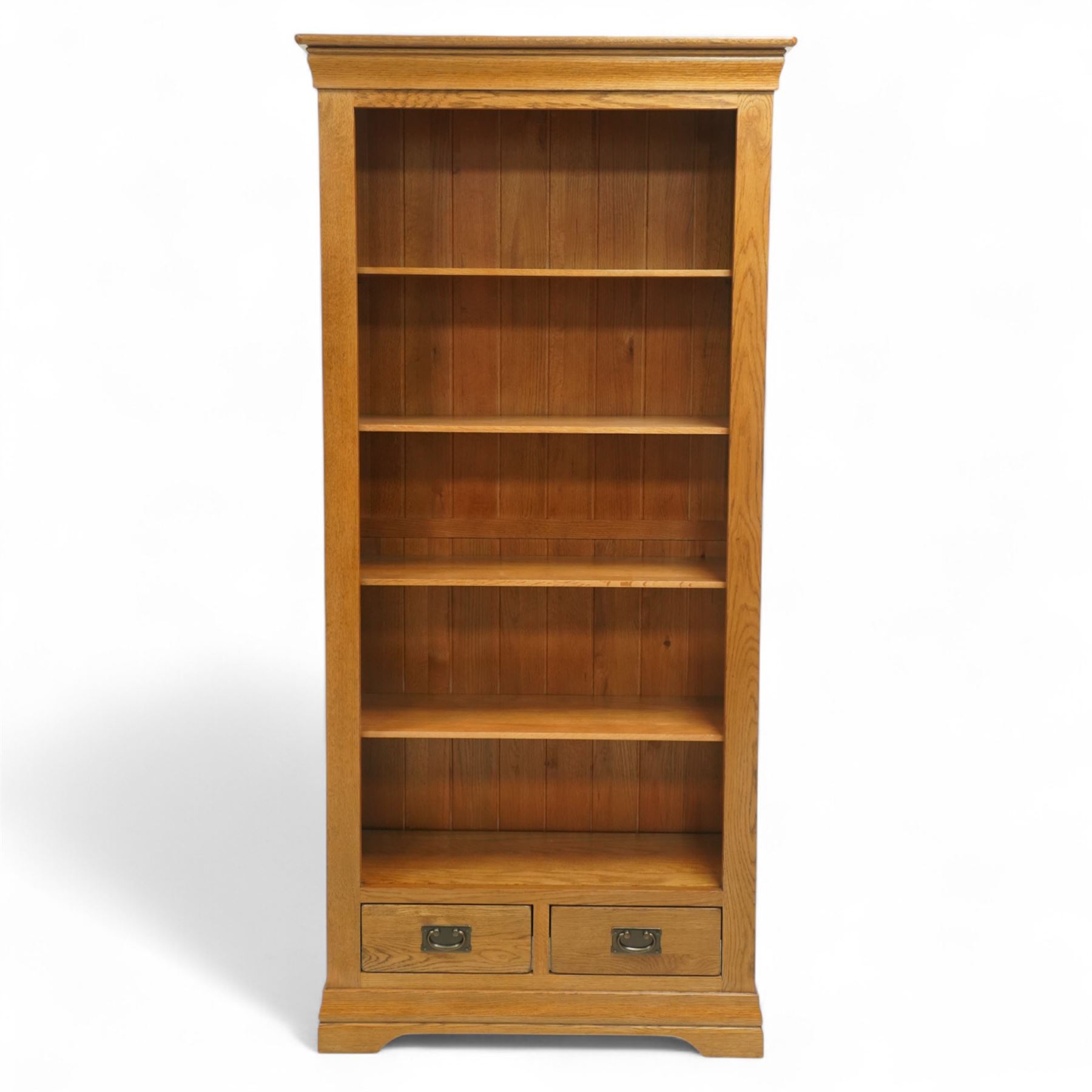 Contemporary oak bookcase, with moulded cornice above open shelved interior, fitted with four adjustable shelves and two short drawers with inset brass handles, panelled sides, plinth base