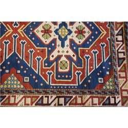 Caucasian Kazak indigo and vermillion ground rug, the geometric field boldly woven with two medallions interspersed with symbolic tribal motifs and shapes, with contrasting ivory guard band