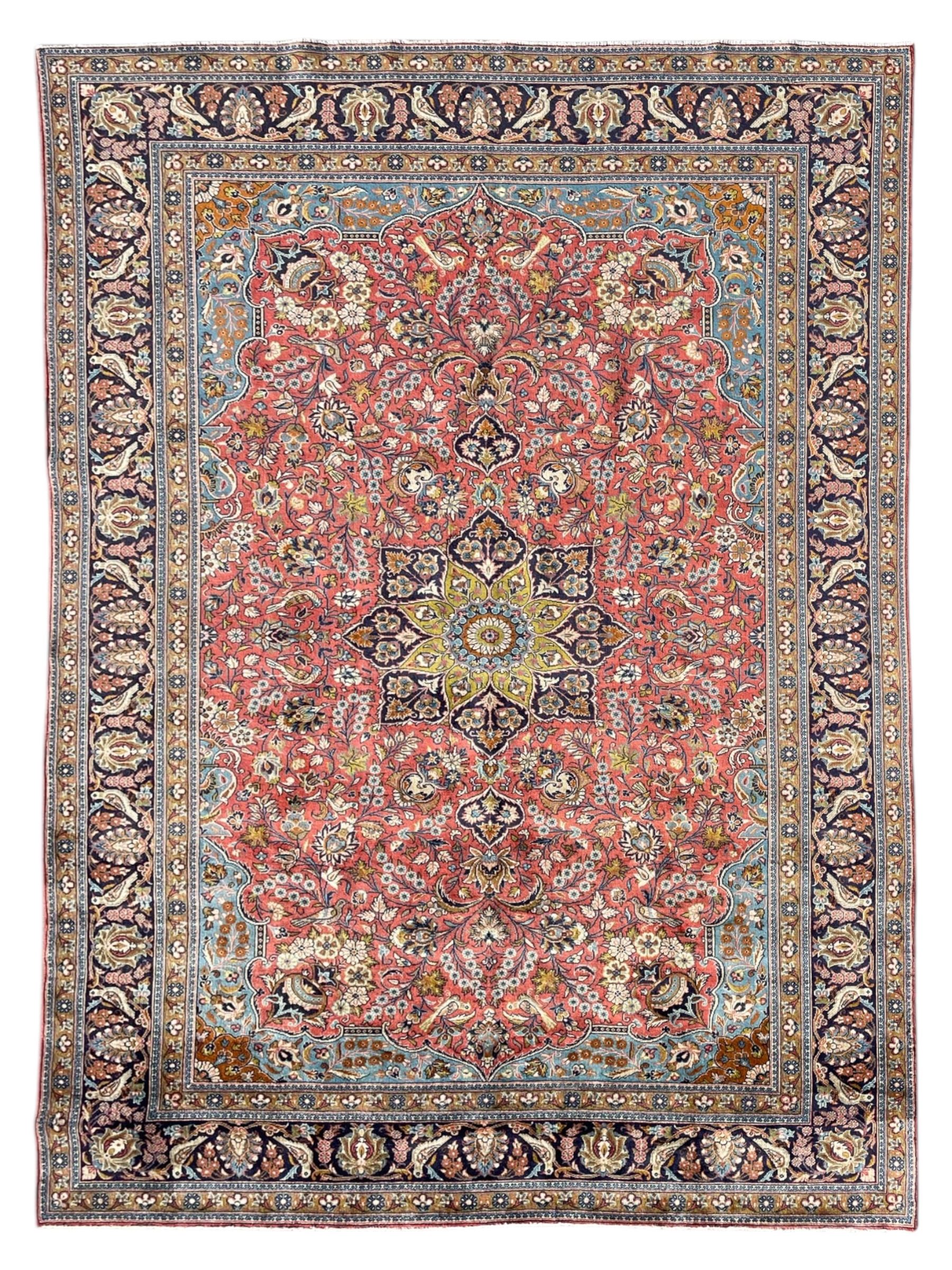 Persian Kashan peach ground rug, central rosette medallion surrounded by trailing branches and flower heads with bird motifs, light blue spandrels with further floral decoration, the main border with repeating palmettes and birds, within guard stripes