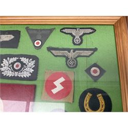 Framed display of thirty-four WWII German cloth badges including Luftwaffe pilot, Paratrooper, Afrikakorps cuff title, sleeve insignia for 'SS' Foreign Volunteers, various breast eagles including Luftwaffe, Army etc, RAD badges, Party Armband, rank and trade insignia, cap insignia etc; 40 x 50cm in modern pine frame