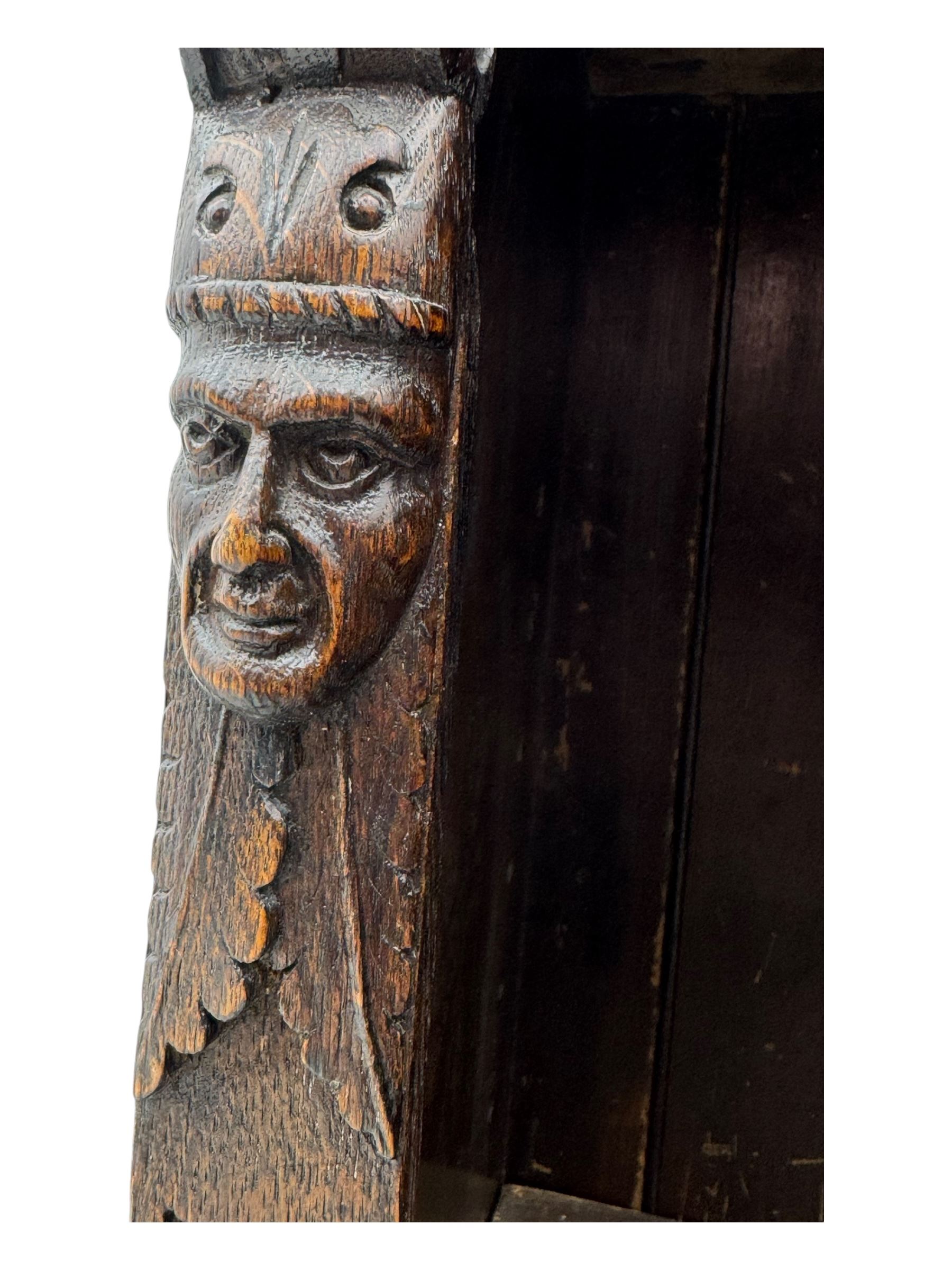 Victorian carved oak corner bookcase, L-shaped form, moulded top over lunette carved frieze, decorated with S-scroll and mask carved corbels with trailing acanthus leaves, fitted with adjustable shelves, on moulded plinth base 