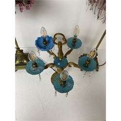 Brass table lamp, modelled as a candelabra with five branches, each with blue glass candle holders with crystal drops, H47cm, together with a pair of cast metal table lamps with acanthus leaf detail, upon a stepped square base, with red fabric feather and tassel shades, H78cm