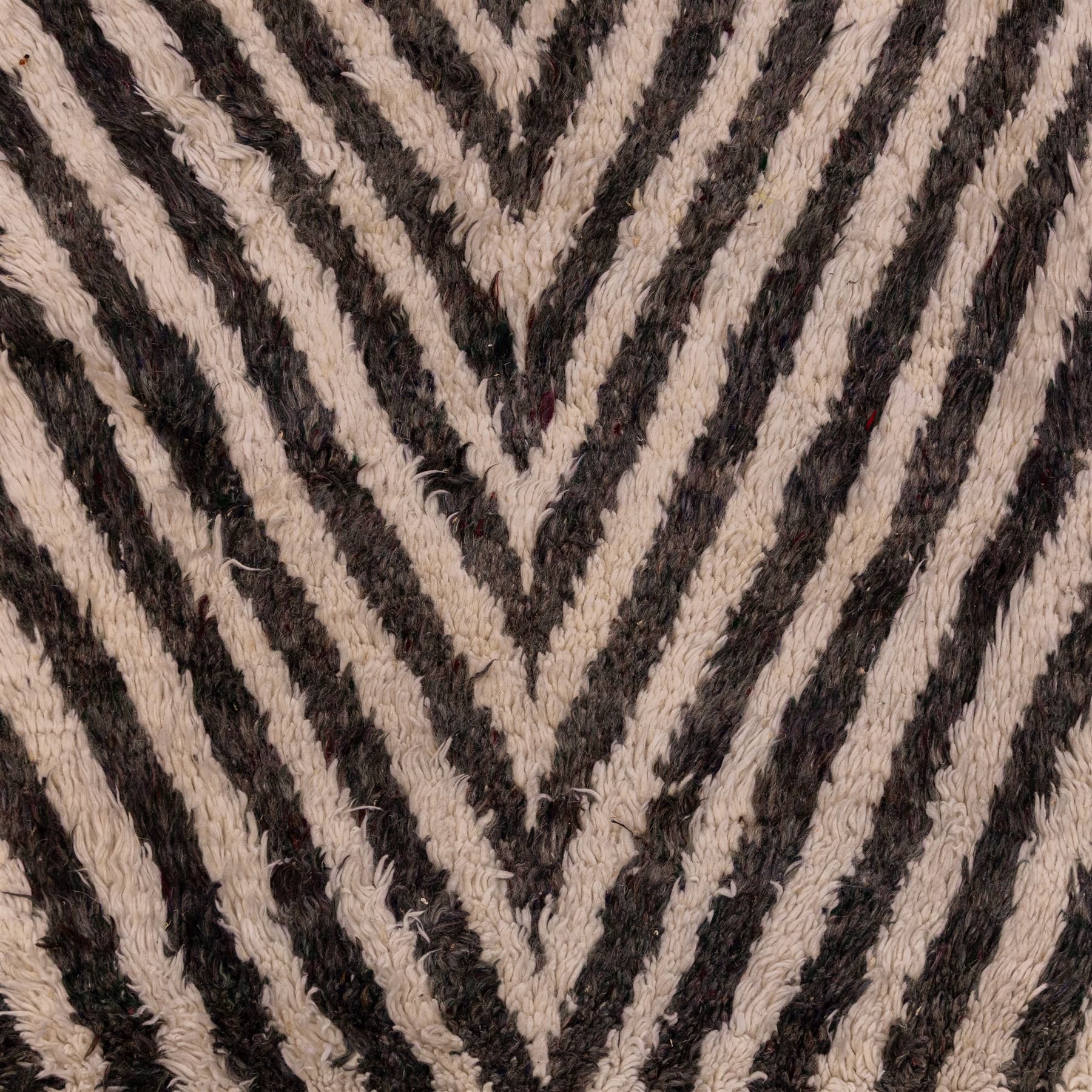 Moroccan Berber hand-knotted rug, of rectangular form, ivory ground decorated with bold, repeating lozenge motifs defined by alternating charcoal grey linear bands, with a striking geometric lattice and chevron with diamond designs, enclosing smaller stylized devices in soft blush tones, with fringe ends