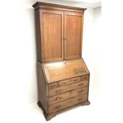 Georgian oak bureau bookcase, projecting cornice, two doors above single fall front enclosing fitted interior above three short and three long graduating drawers, ogee bracket supports 