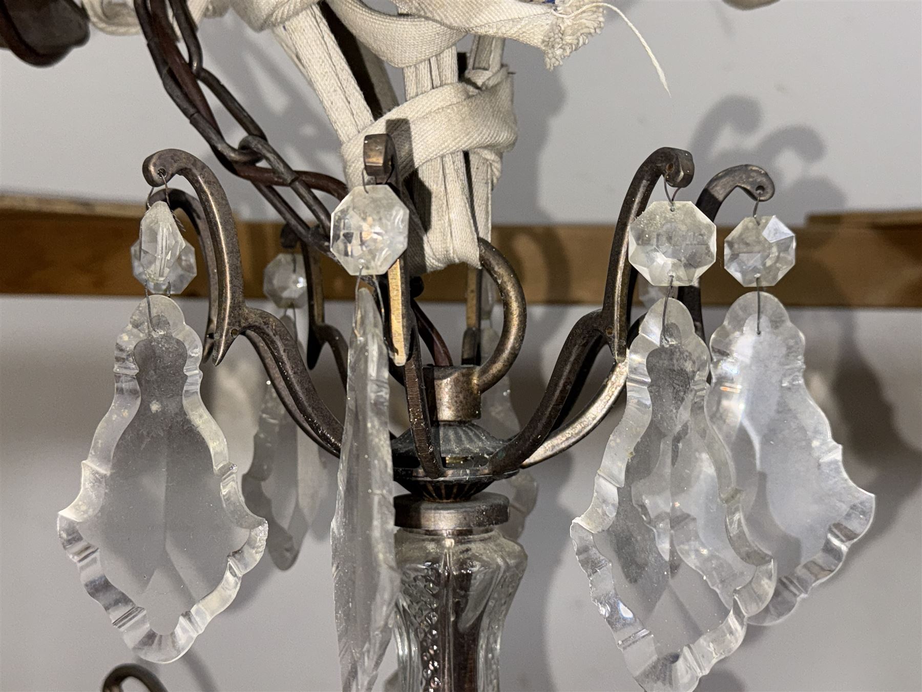 Early 20th century continental cut glass and metal chandelier, with sixteen candle style lights on a single tier of scrolled arms, hung with faceted glass drops and centred by a mould-blown and cut glass baluster stem, suspended from a ceiling rose and chain