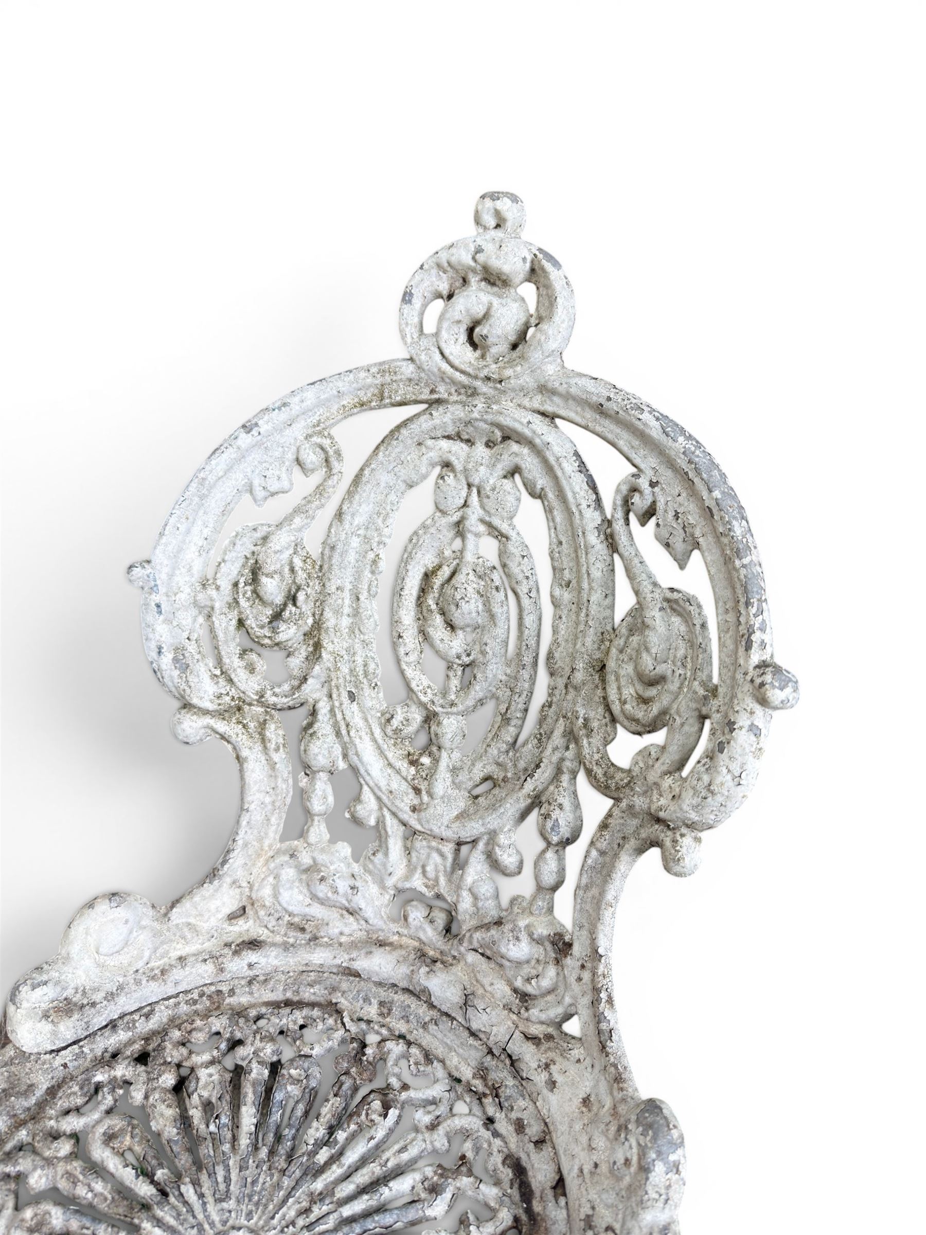 Pair of white painted cast metal garden chairs, ornate reclined backs, circular pierced seats on cabriole legs