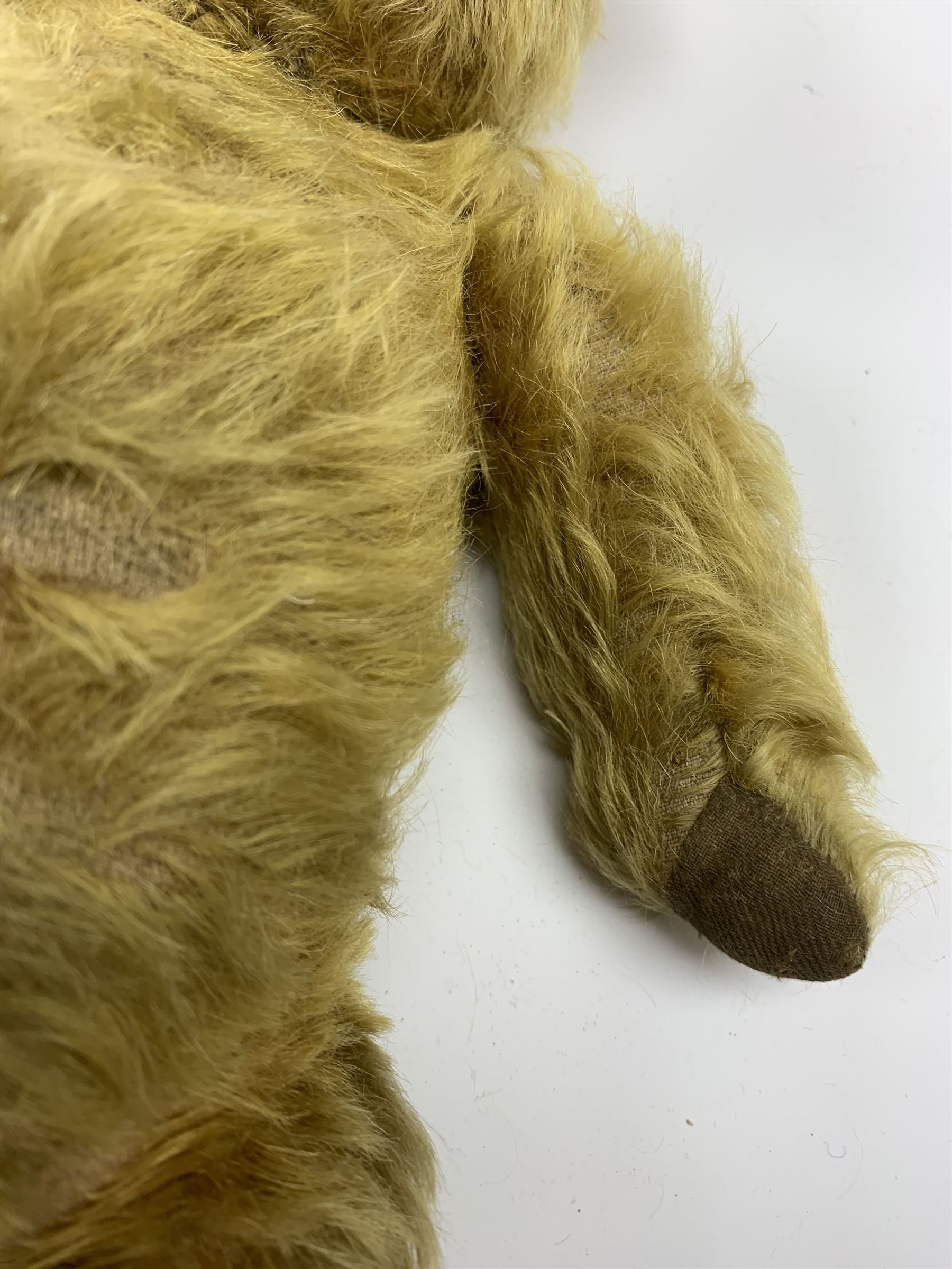 Early 20th century English teddy bear, WW1 period, with wood wool filled mohair body, fixed head with one boot button eye and vertically stitched nose and mouth and jointed limbs with cloth paw pads H16