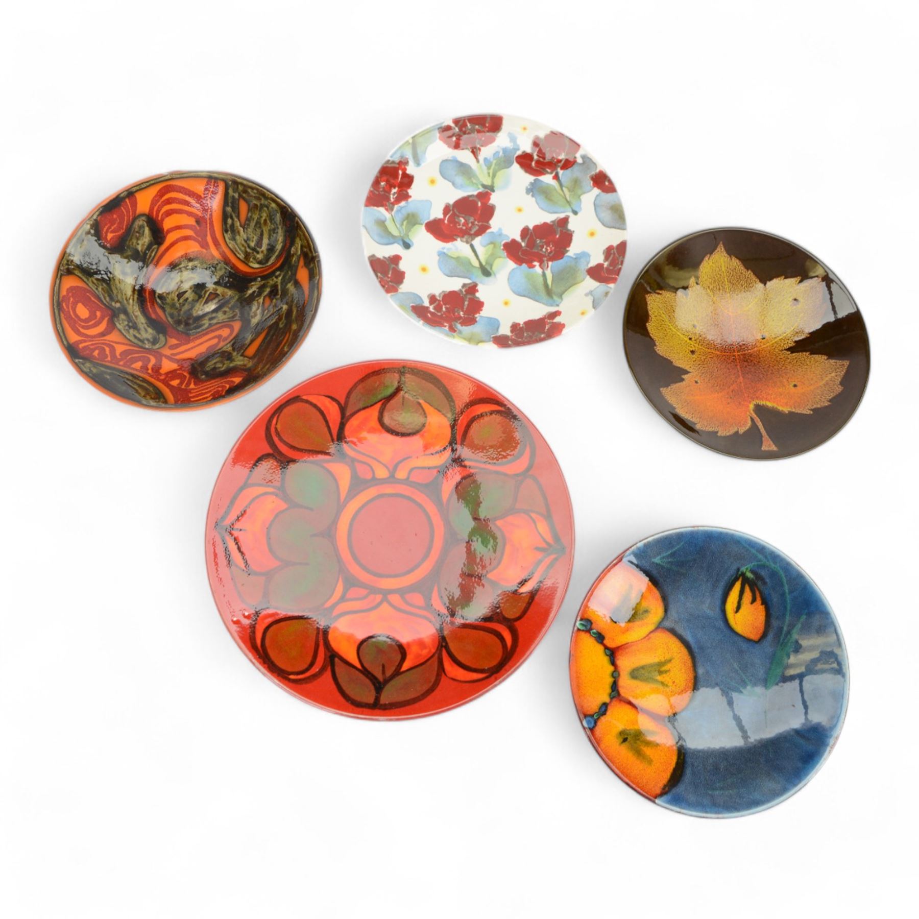 Three Poole pottery chargers, in Wild Poppy pattern, Delphis pattern and Aegean pattern, together with a Poole pottery dish and plate  