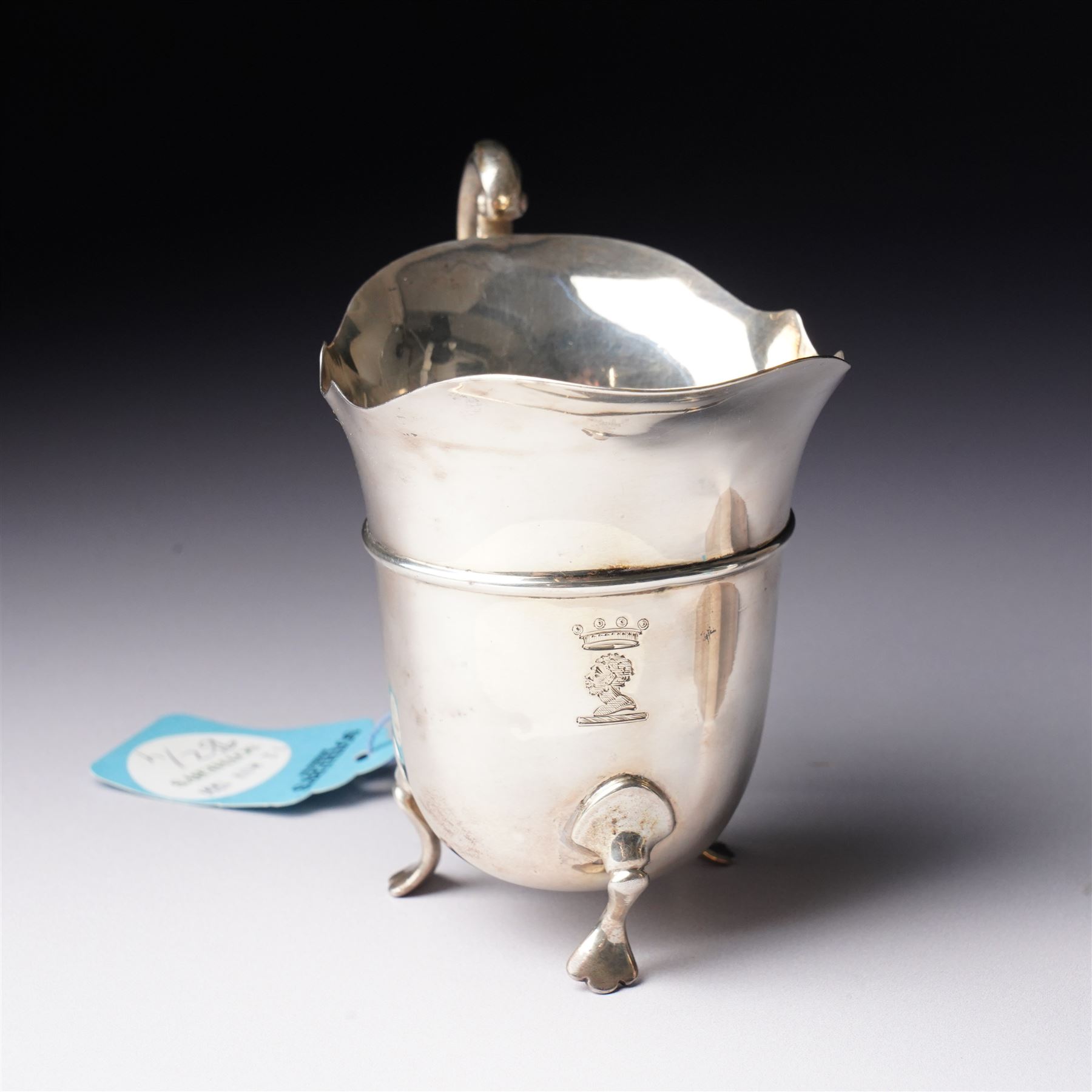 Silver square tea caddy with hinged lid and canted corners H9cm Birmingham 1912 Maker Synyer & Beddoes and a silver cream jug with crimped rim and scroll handle engraved with a crest  London 1901 Maker William Hutton & Sons