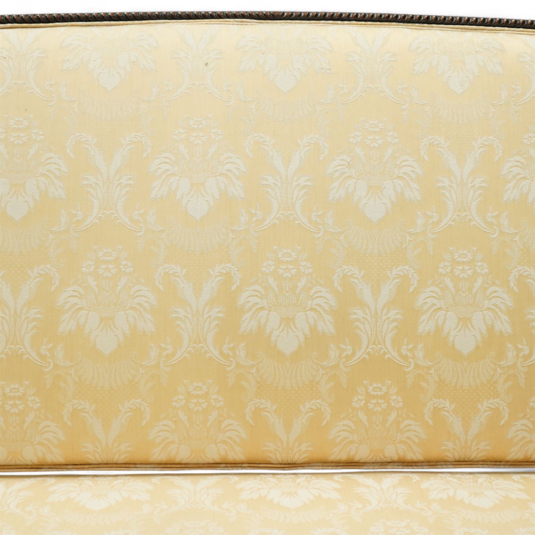 Early 20th century mahogany settee in the George III style, upholstered in pale yellow damask fabric, moulded serpentine seat rail with carved foliate detail, on cabriole supports with acanthus carved knees and scroll feet