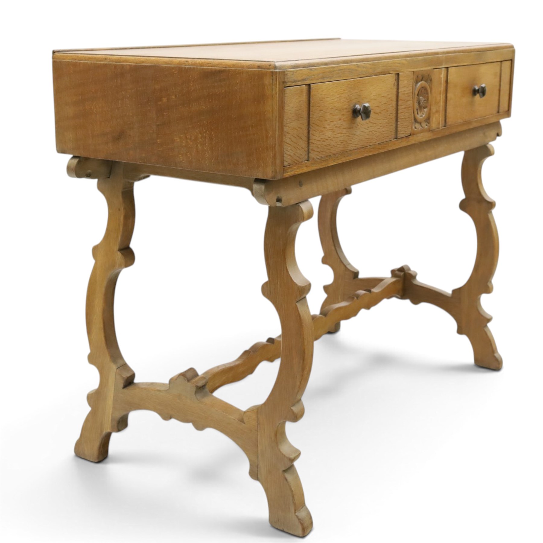 Leemings of Halifax (est. 1872) - Arts & Crafts oak side table, rectangular caddy top with raised moulded back, the frieze carved with central Yorkshire rose motif flanked by two drawers, raised on twin stylised lyre end supports formed of C-scrolls, united by shaped stretcher