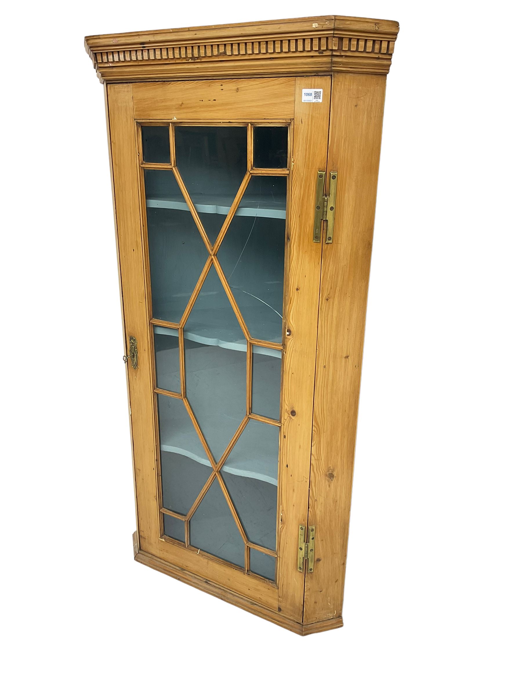 Early 19th century pine corner cabinet, projecting dentil cornice over astragal glazed door