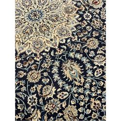 Persian Kashan indigo ground carpet, the central ivory rosette medallion surrounded by trailing and interlaced flower heads and branches, matching spandrels with floral design, the border with scrolling pattern decorated with stylised plant motifs within guards