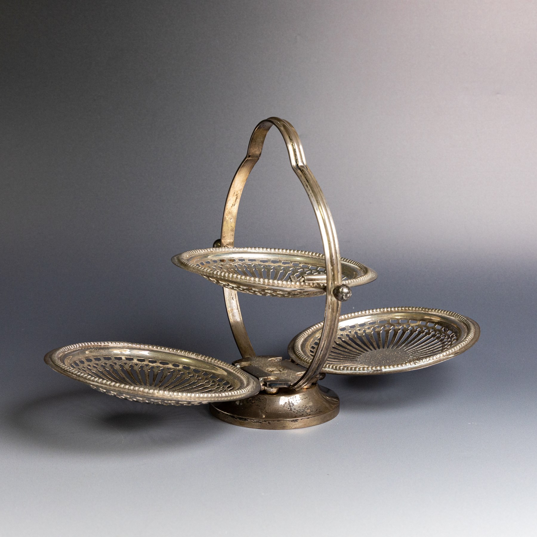 Indian silver folding cake stand, of circular form with pierced decoration, loop handle and circular foot, when folded H18cm