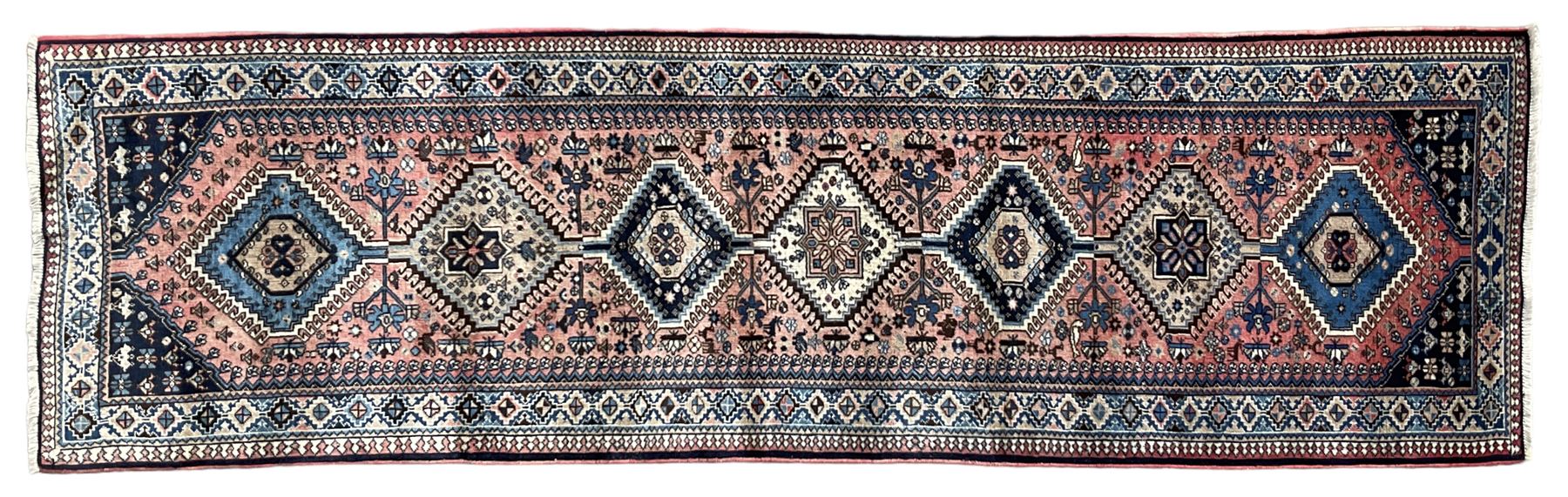 Persian Yalameh coral ground runner rug, the field decorated with seven hooked lozenge medallions surrounded by stylised plant motifs, the indigo spandrels decorated with similar patterns, guarded border with repeating diamond lozenges