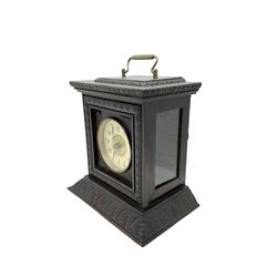 German - late 19th century  Black Forest Junghans alarm clock, profusely carved mouldings with glass side panels and carrying handle, two part dial with a gilt centre, Arabic numerals, minute track and steel spade hands, 30hr  balance wheel movement with alarm sounding on a bell, wound and set from the rear, with Key.