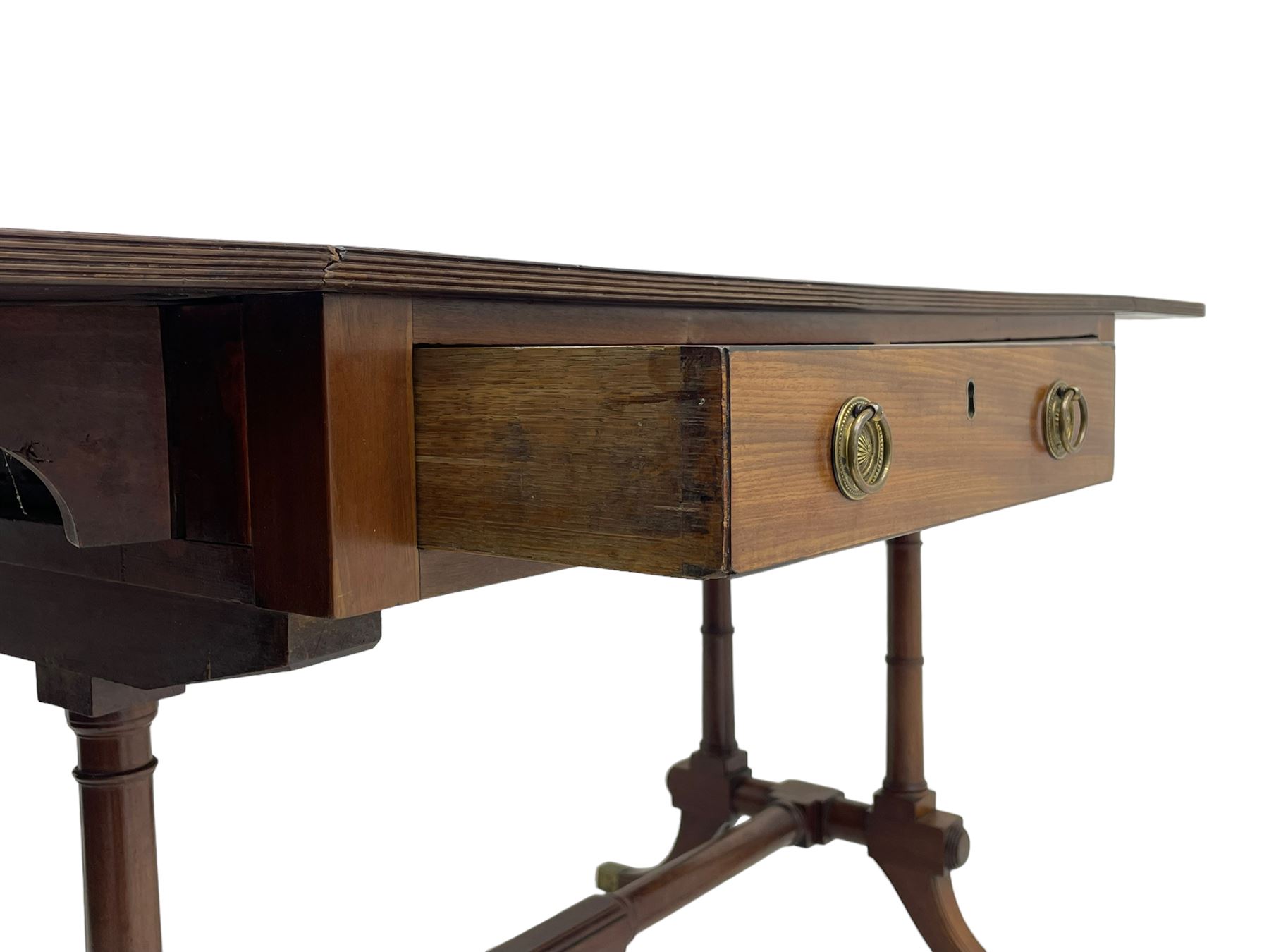 George III mahogany sofa table, rectangular drop-leaf top with reed moulded edge and rounded corners, fitted with two frieze drawers and two opposing false drawers, quadruple collar turned pillar supports on turned and block platforms, splayed and moulded supports with brass cups and castors 