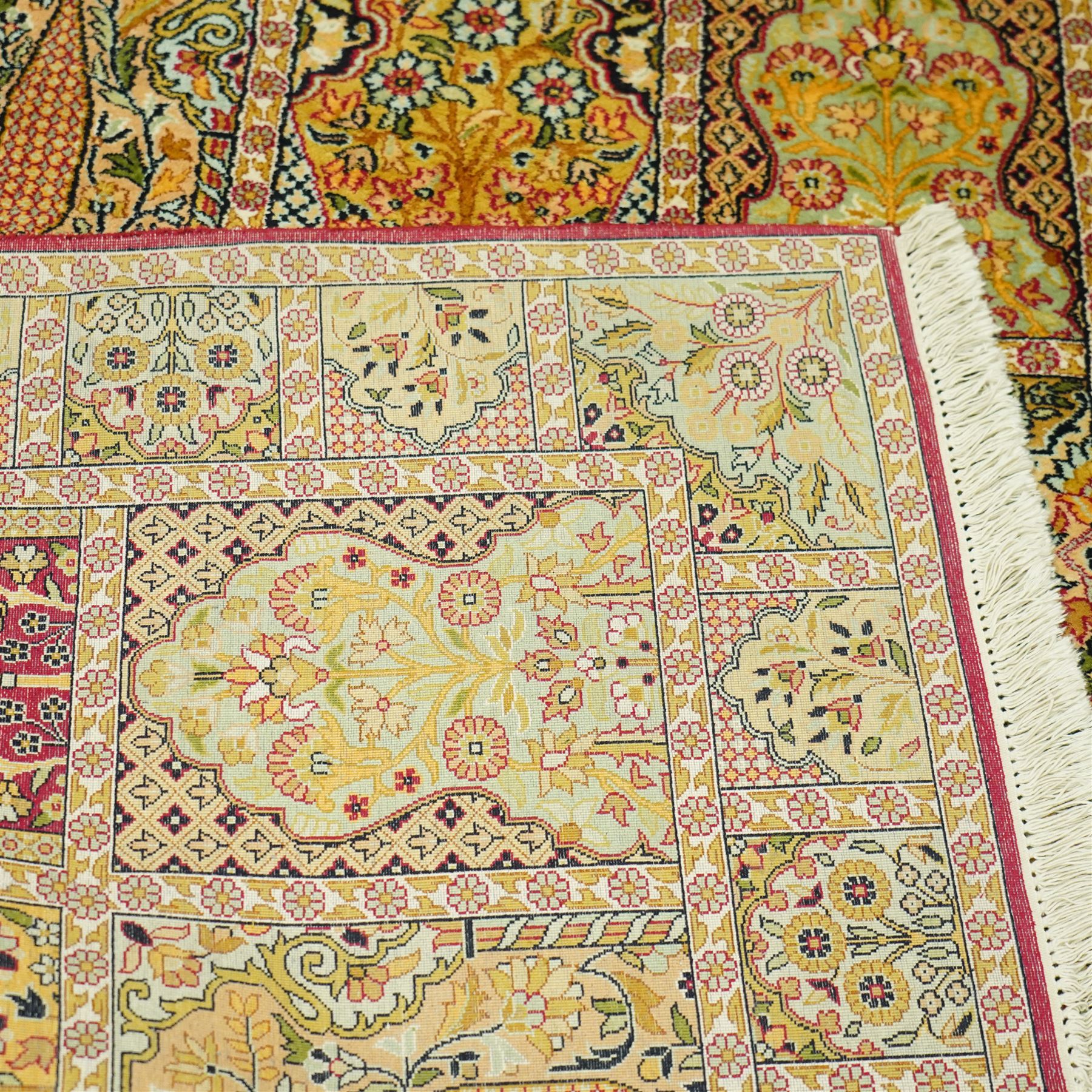 Late 20th-century Persian panel design silk and cotton blend rug, in pale tones of ivory, pistachio, green, crimson, pale blue, and rose, each compartment enclosing a stylized mihrab, boteh, cypress, and floral motifs, framed by a narrow floral border with guard stripes and cotton fringe ends 