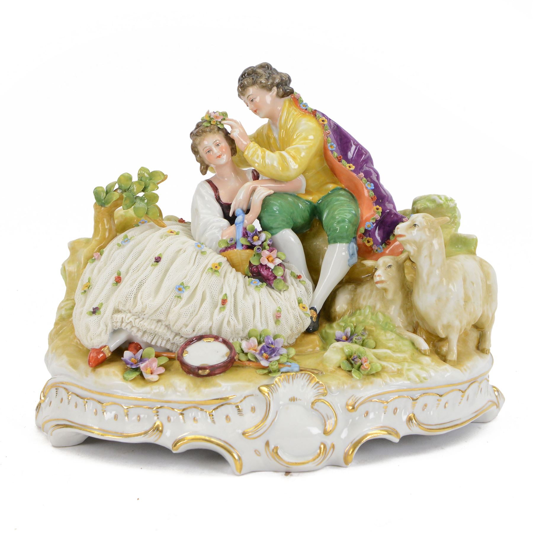 German lace figure group, modelled as a courting couple upon a naturalistically modelled base with gilt scroll edge, further detailed with two goats, encrusted flowers and tambourine, the female figure with lace flower encrusted skirt, with printed marks beneath, H21cm W26cm