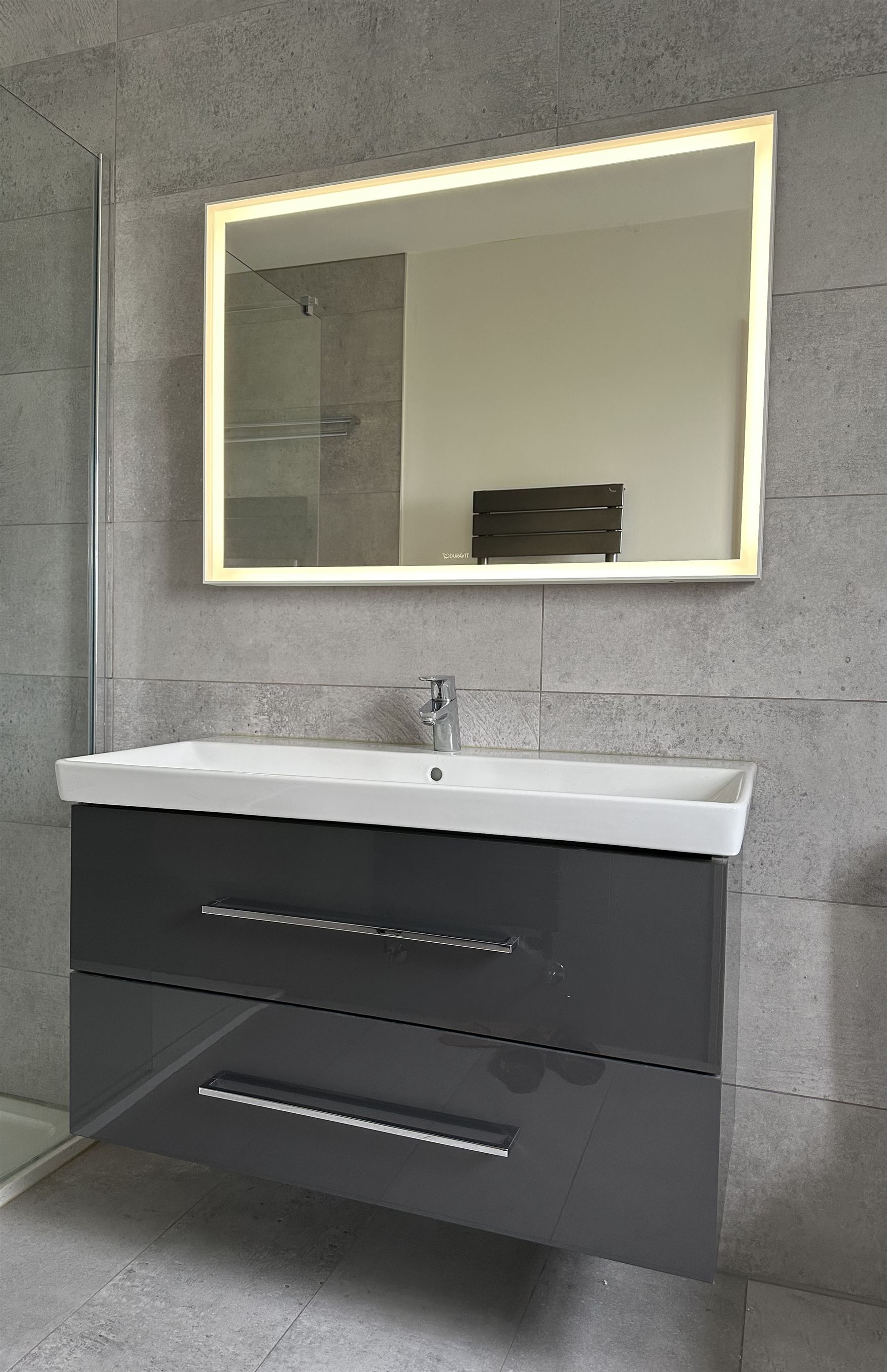 Villeroy & Boch vanity unit, ceramic hand basin with Hansgrohe mixer tap on two drawer wall mounted unit in gloss grey finish L101cm D47cm H58cm. Complete with Duravit illuminated wall mounted mirror in white frame 100cm x 70cm