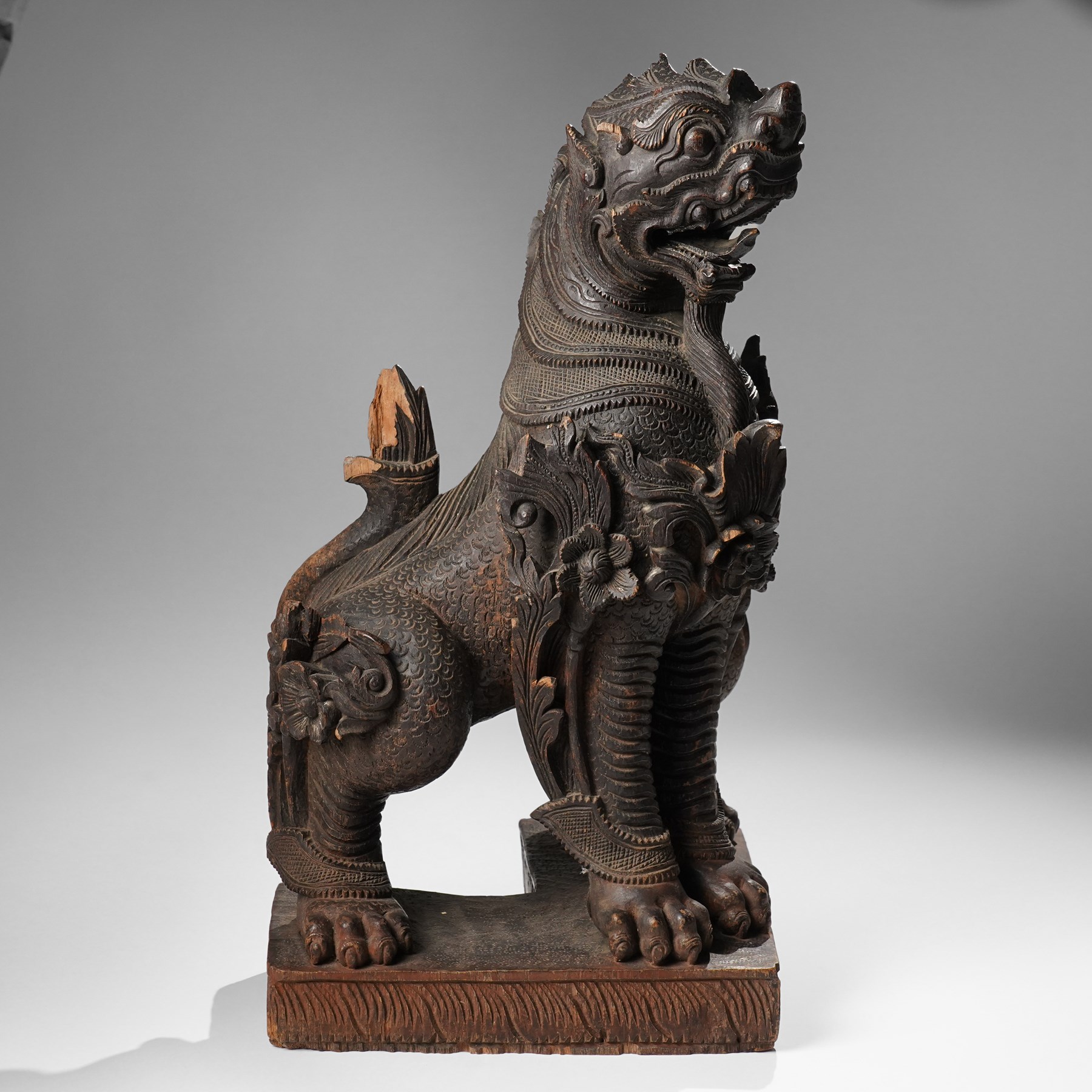 Burmese carved temple guardian figure, depicted seated with carved flame details, H52cm 