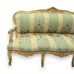 20th century French Louis XV style giltwood salon sofa, with shaped and moulded serpentine cresting rail carved with central scroll motif, padded back and seat upholstered in green and gold striped damask fabric, scroll carved open arms with padded rests, shaped apron carved with rocaille and foliate motifs, raised upon cabriole legs