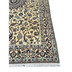 Persian ivory ground rug, the  large floral medallion within a field decorated with scrolling branches with clusters of flower heads, the matching ivory border with palmette motifs and interlaced scrolling