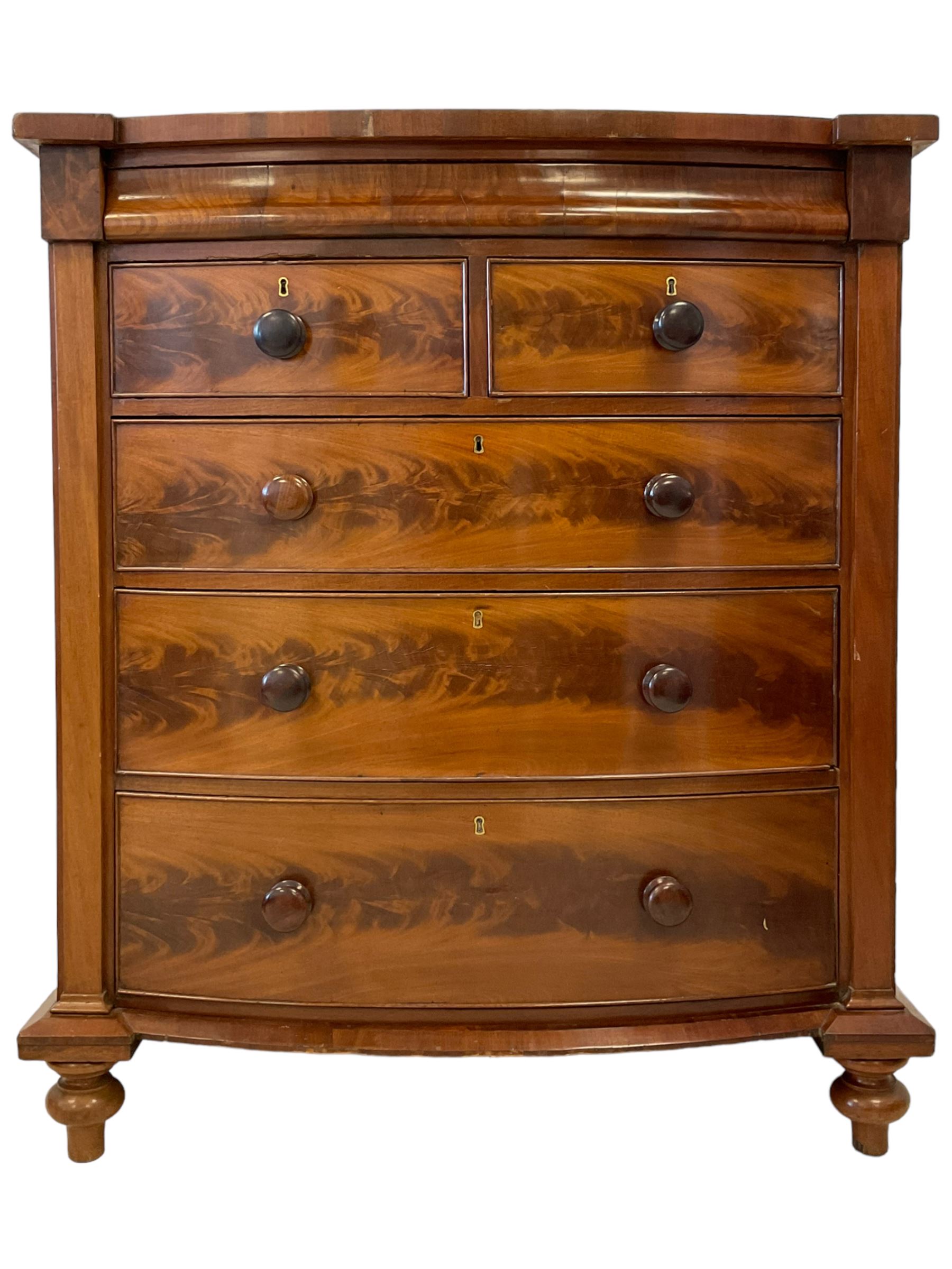Late 19th century mahogany bow-front chest, fitted with banded cushion drawer with secret catch, above two short over three long graduating drawers, each cock-beaded with turned handles, lower moulded edge over turned feet