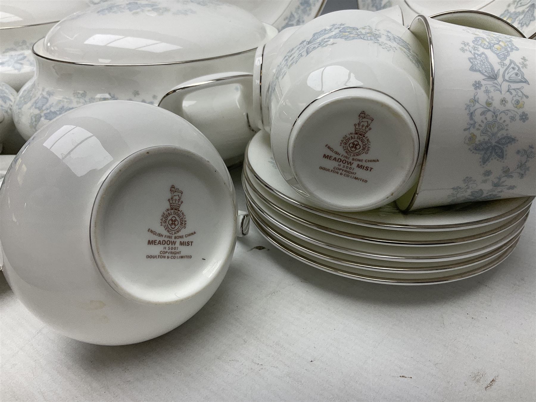 Royal Doulton tea and dinner wares in the Meadow Mist pattern, no H5007, comprising seven dinner plates, eight side plates, two lidded tureens, two jugs, lidded sucrier, oval serving dish, six teacups, seven saucers, seven tea plates and large saucer