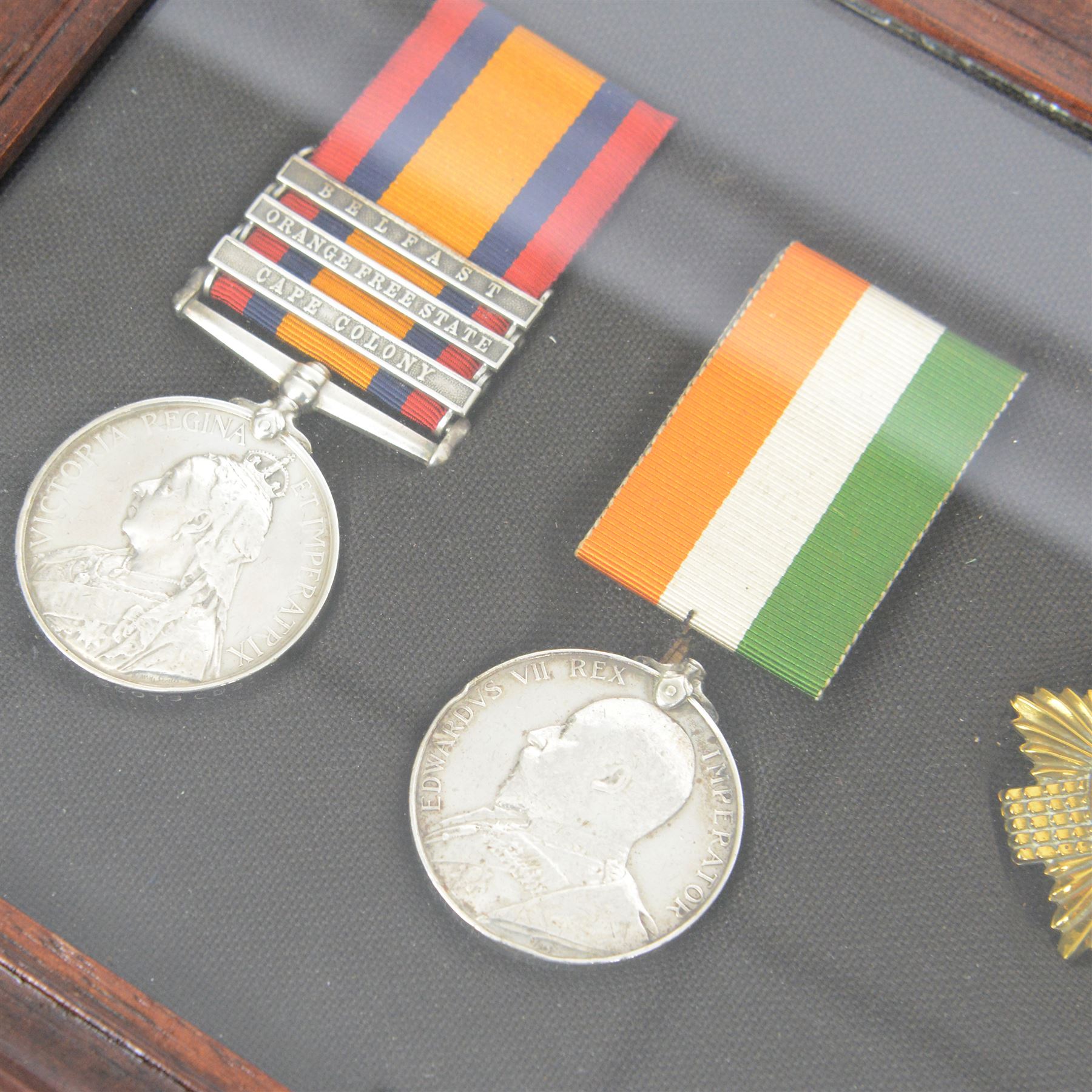 Victorian Queens South Africa Medal with Belfast Orange Free State and Cape Colony clasps, Kings South Africa medal, awarded to 72 Pte W Wilson Scots Gds and WWI war medal and 1914 star, awarded to 9335 Pte W Neilson S Gds, all framed with Scots Guard Beret badge to the centre 