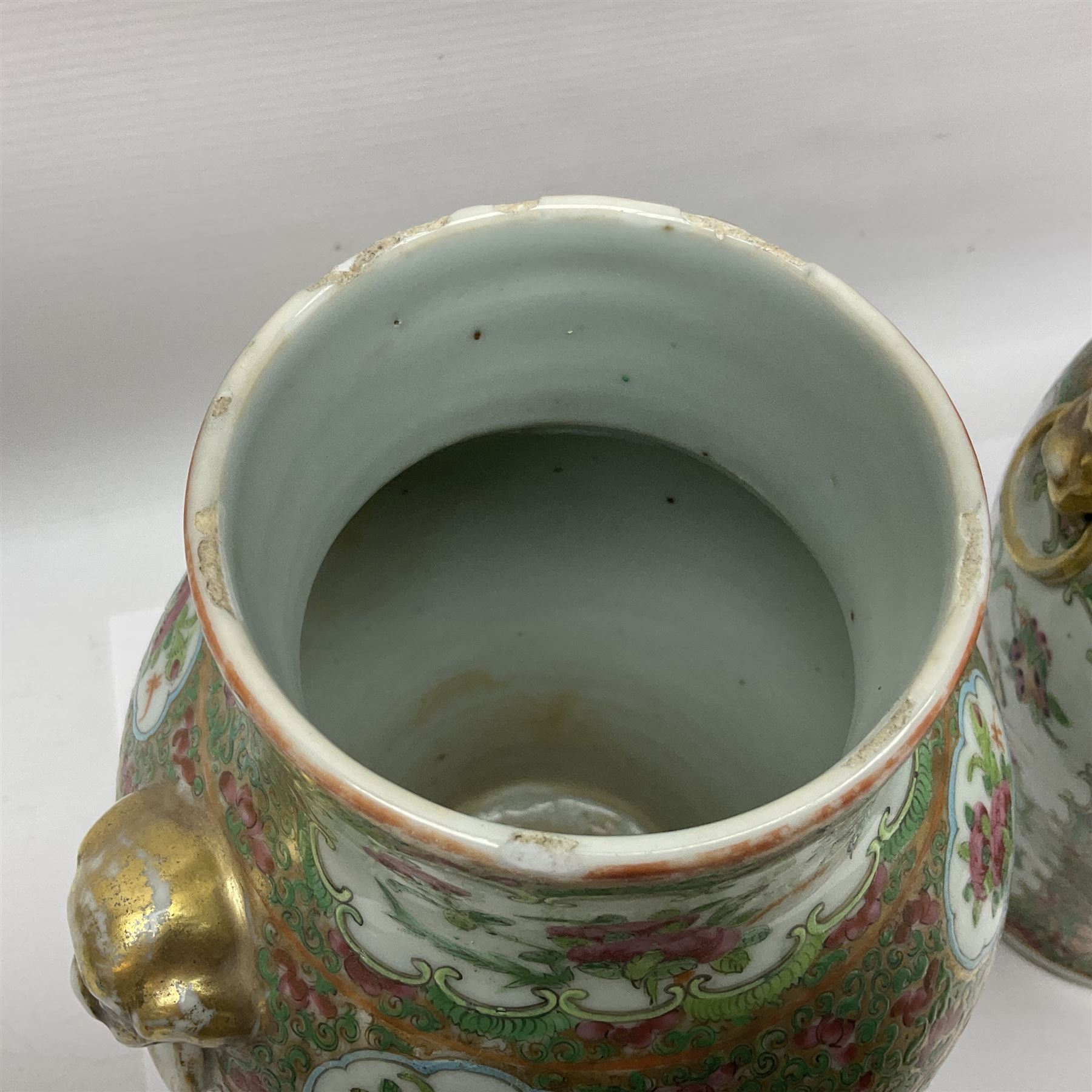 Pair of 19th century Chinese Famille Rose vases and covers, each of baluster form with twin gilt lion mask ring handles to shoulders, the flattened domed covers with gilt temple lion finials, each decorated with alternating reserves of bijin and attendants, and birds and butterflies amongst blossoming peonies, against a gilt ground profusely decorated with stylised scrolls, H32.5cm